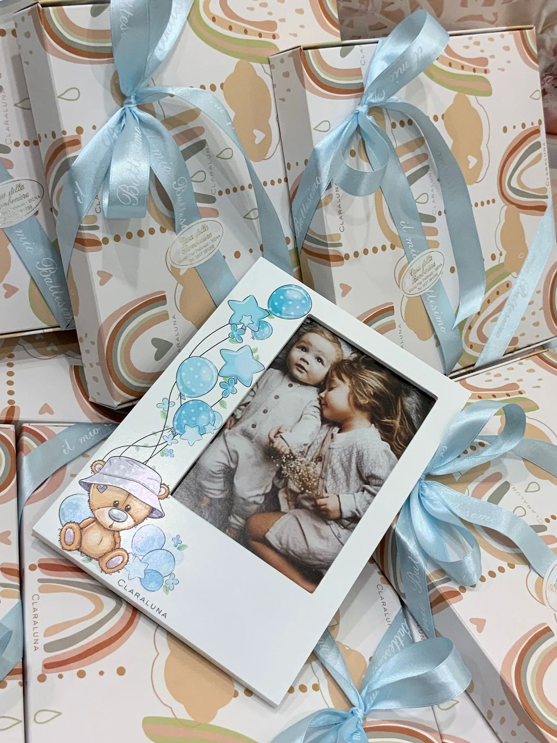 Scatole regalo con nastri blu e biglietto con foto floreale su carta da regalo decorata.