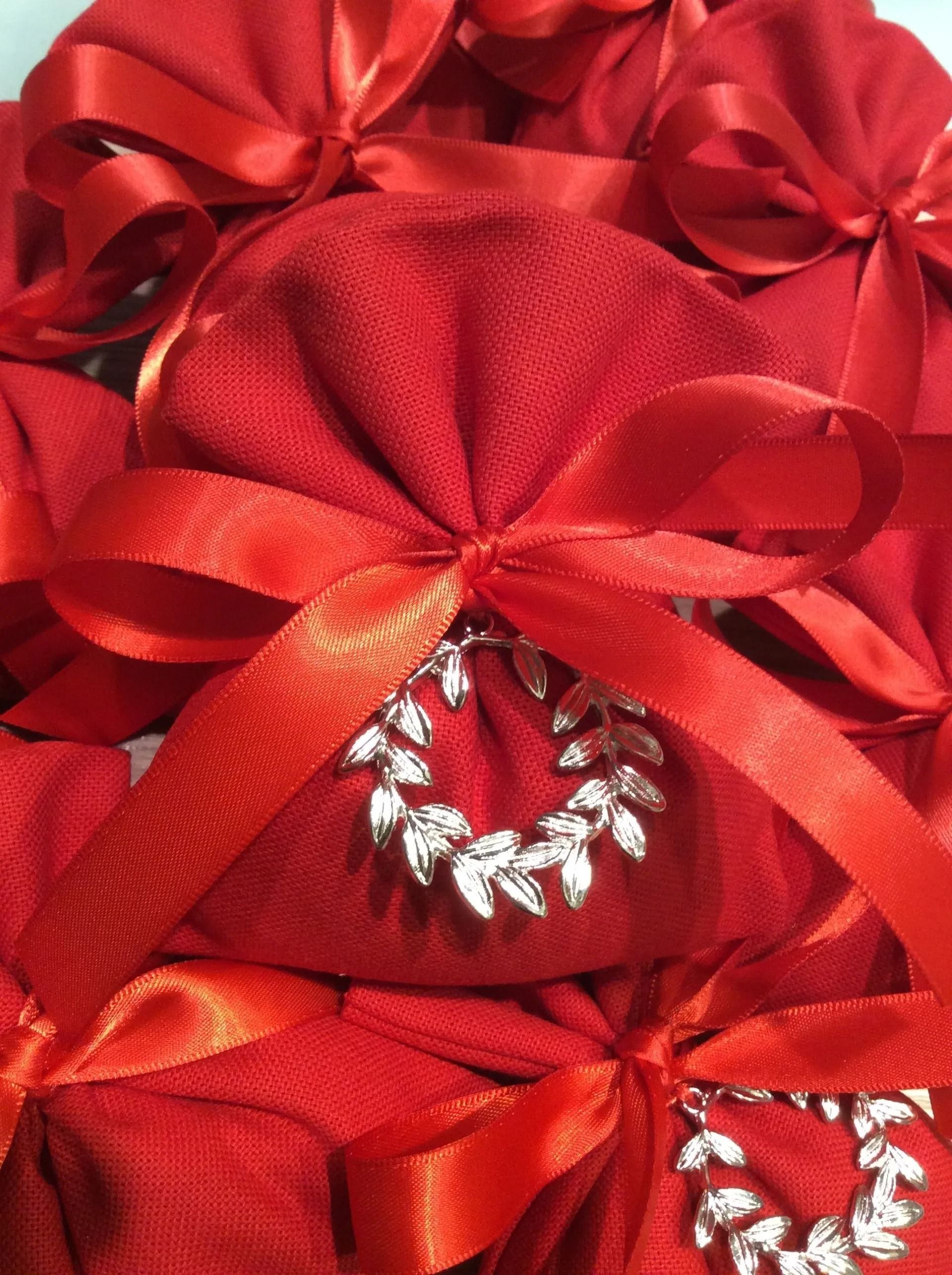 Sacchetti regalo rossi con fiocchi di raso e decorazioni a forma di cuore impreziosite da gioielli.