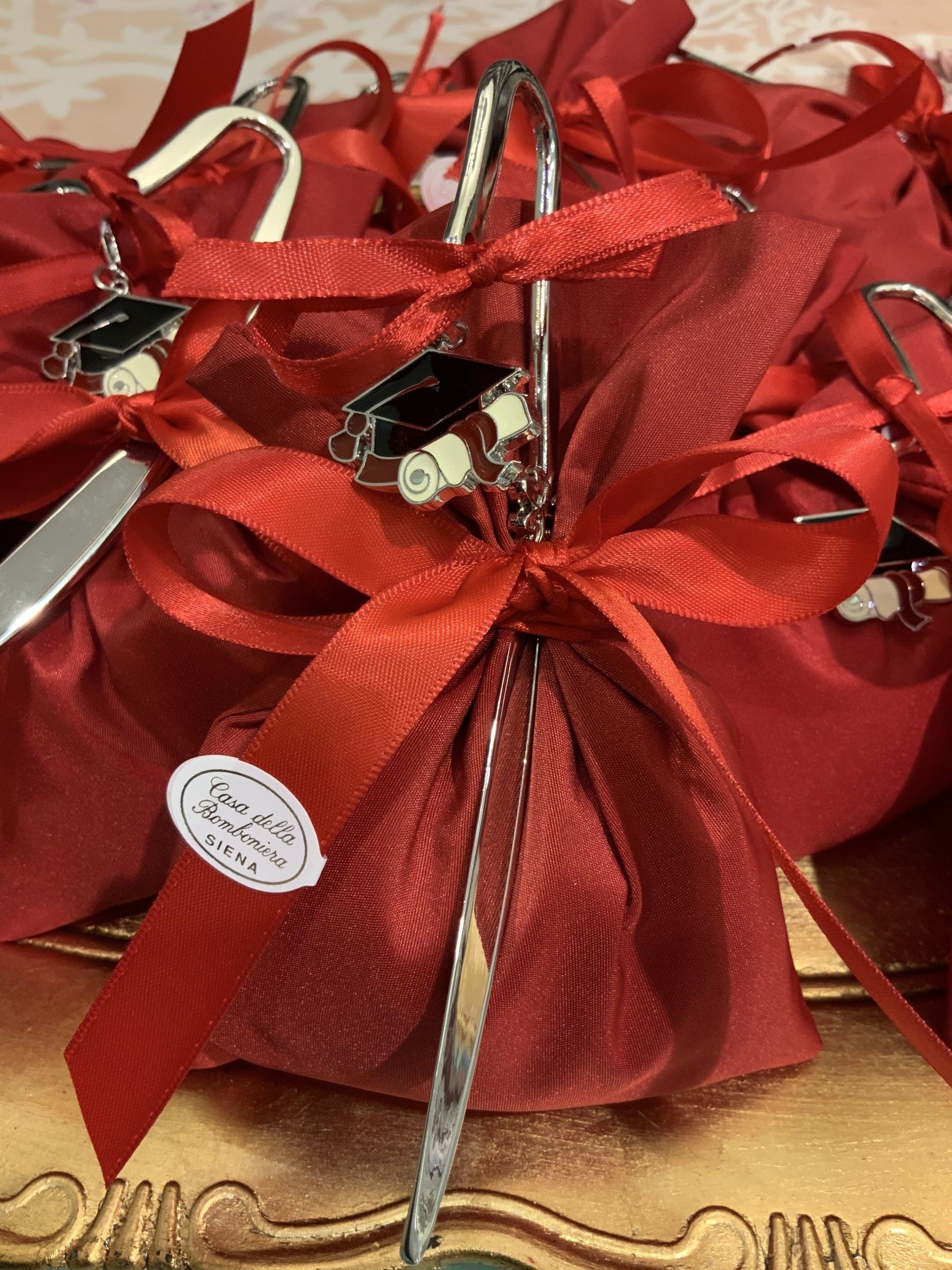 Sacchetti regalo rossi, legati con fiocchi di nastro rosso e manici argentati, su uno scaffale di un negozio.