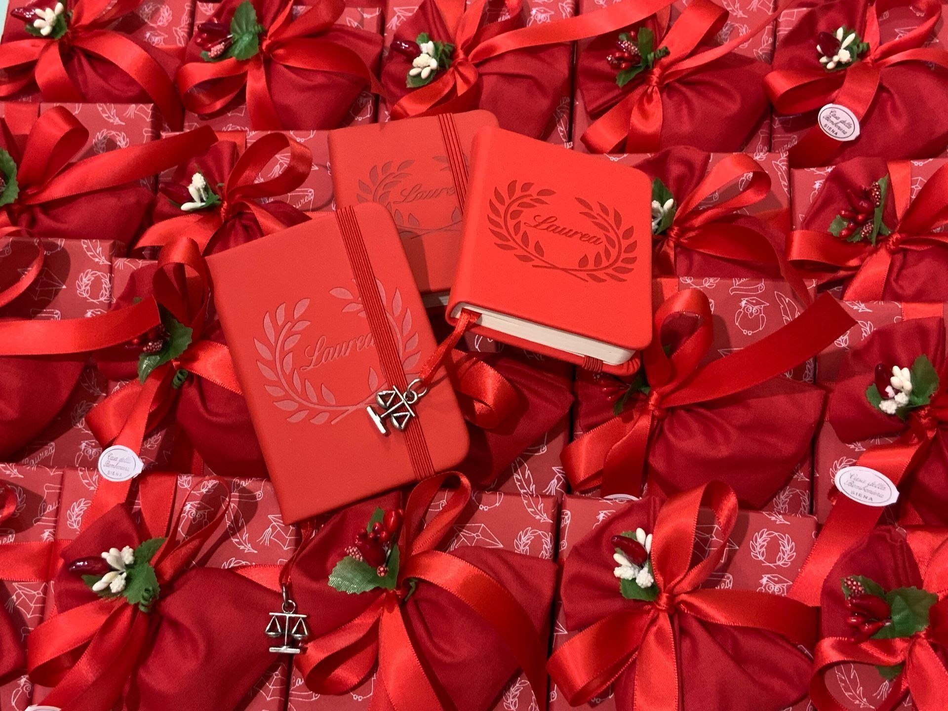 Scatole regalo rosse e fiocchi disposti secondo uno schema festivo, con due buste rosse sopra.