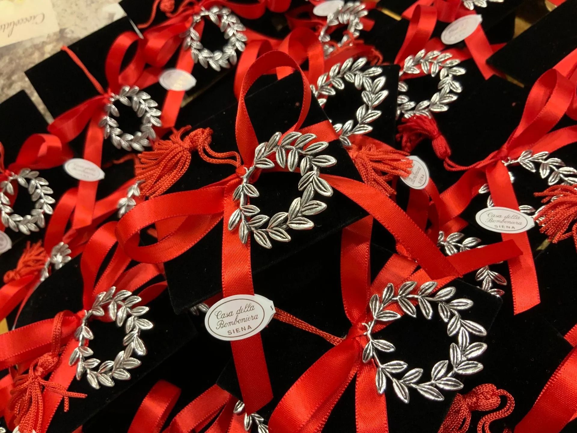 Nastri ornamentali rossi e argento e decorazioni floreali su tessuto nero con dettagli bianchi a forma di cuore.