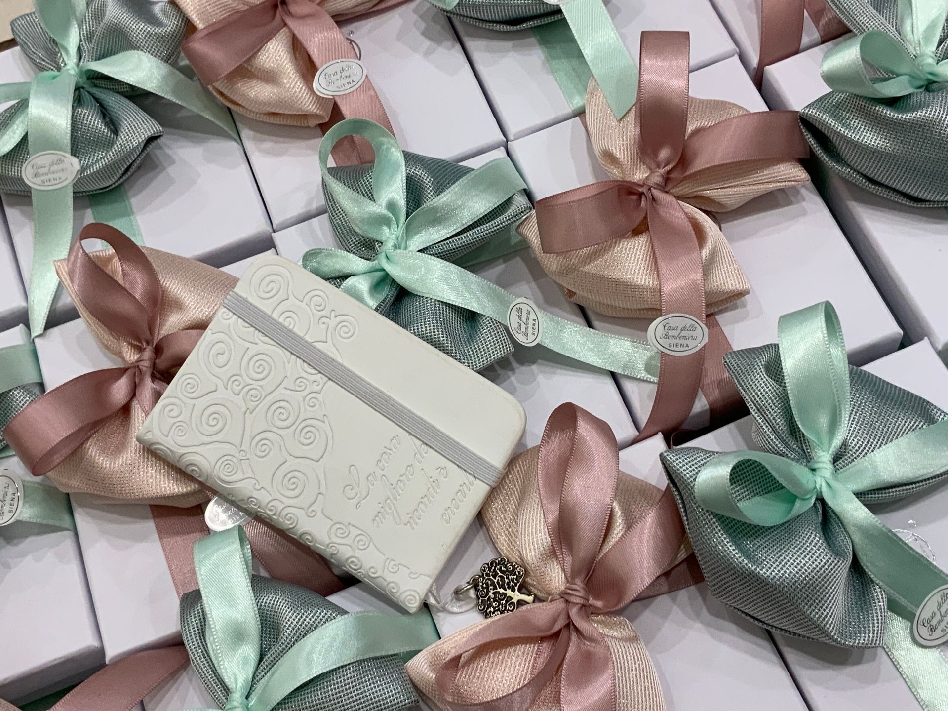 Scatole regalo con nastri rosa pastello e verde menta disposti secondo un motivo decorativo.