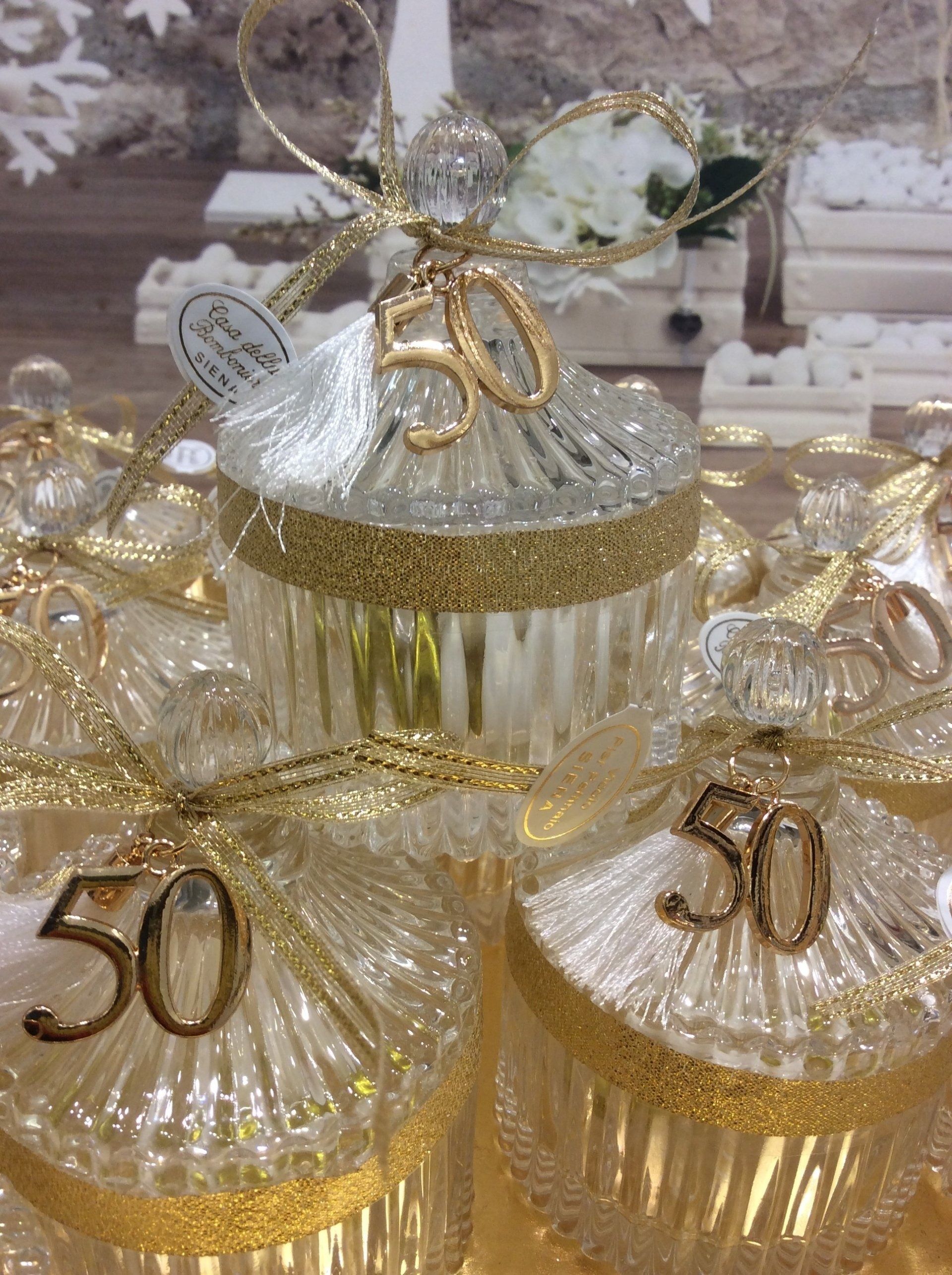 Scatole regalo decorate in oro e bianco con nastri argentati e numero 50 sulla parte superiore.