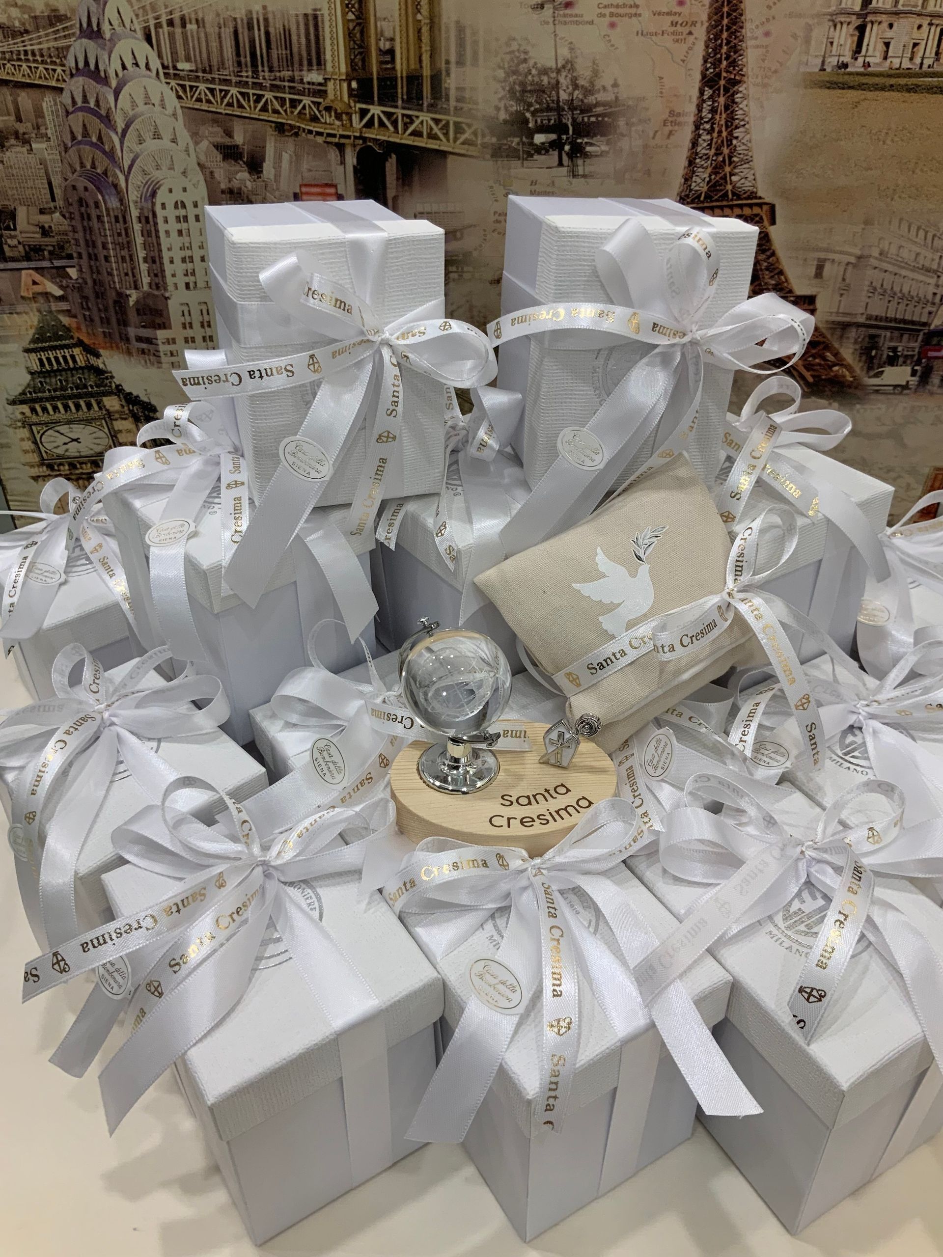 Scatole regalo bianche con nastri argentati disposte in una composizione decorativa su uno sfondo a motivi.