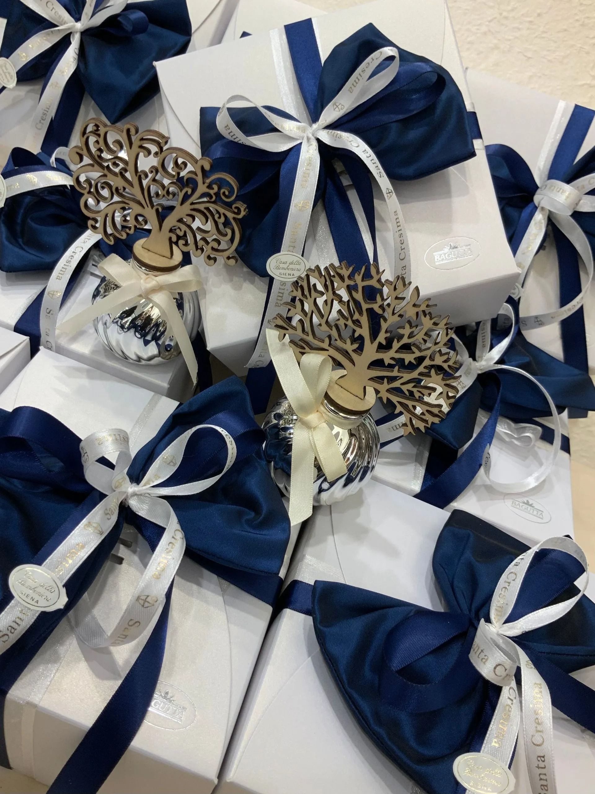 Scatoline bianche per bomboniere con fiocchi di nastro blu navy e decorazioni a forma di farfalla disposte insieme