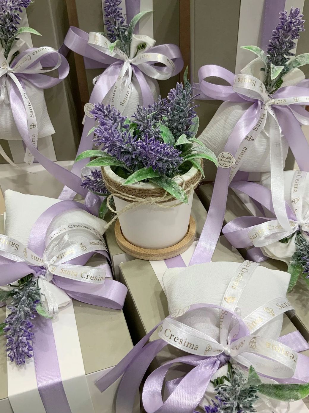 Scatole regalo e fiocchi di lavanda con piccoli vasi di fiori viola disposti insieme