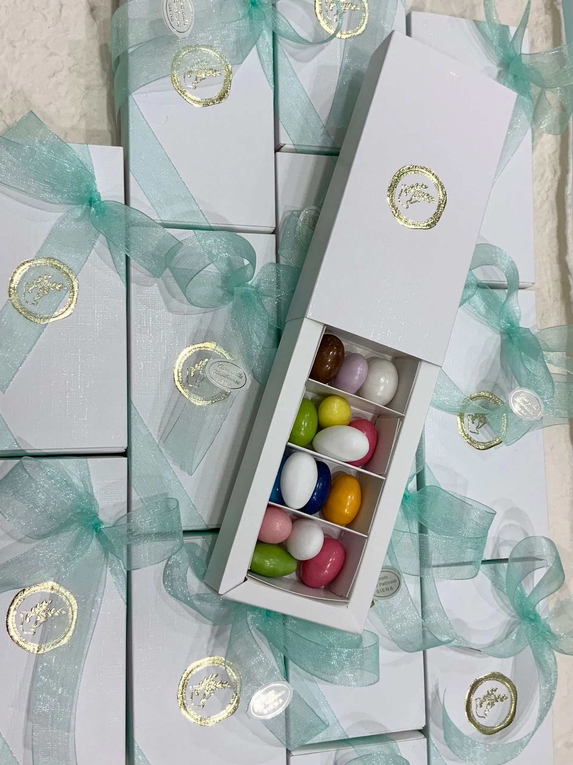 Scatole regalo con nastro color menta e un vassoio di caramelle colorate in una scatola aperta