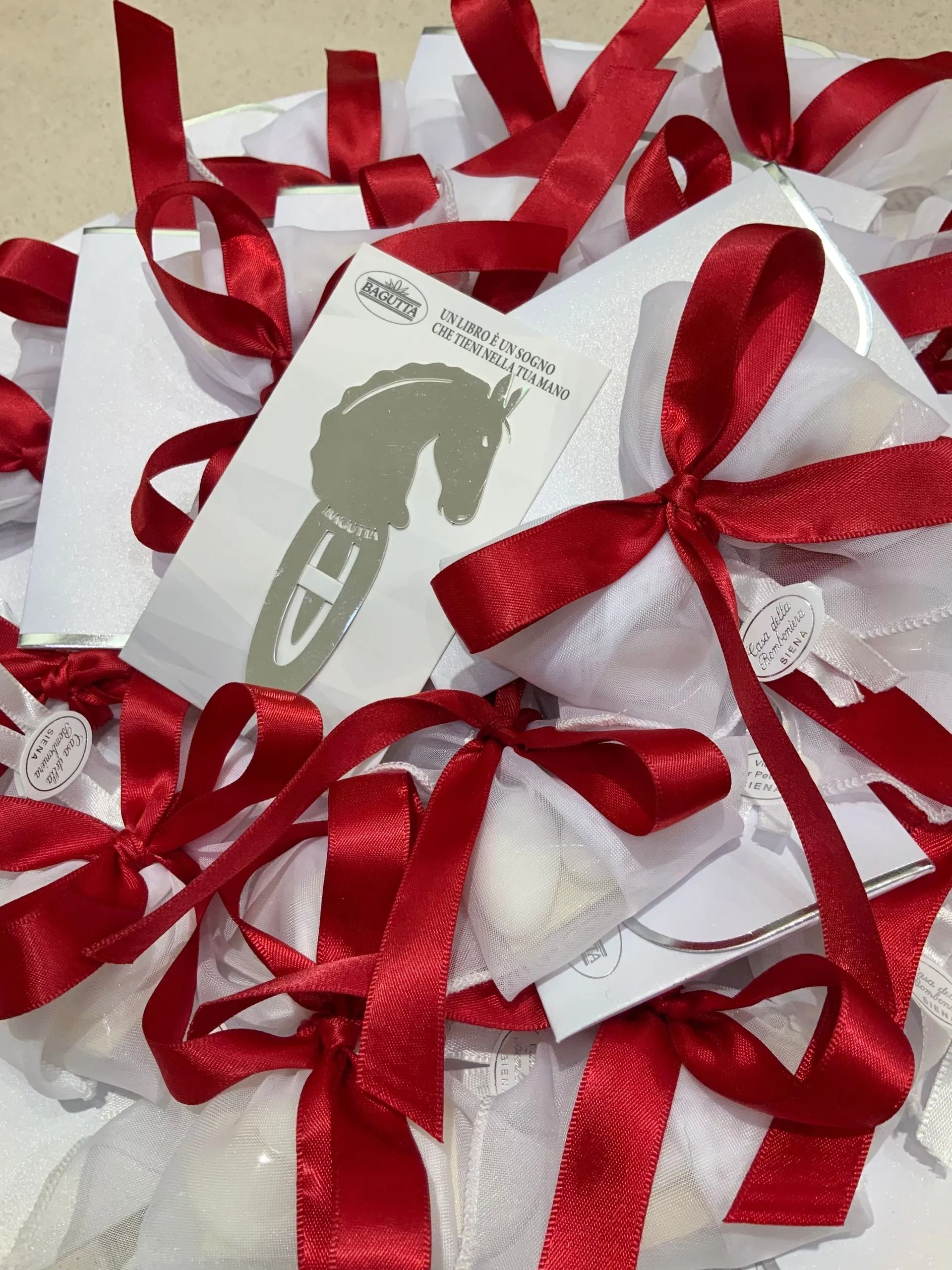 Scatole regalo bianche legate con fiocchi di nastro rosso lucido su una superficie chiara