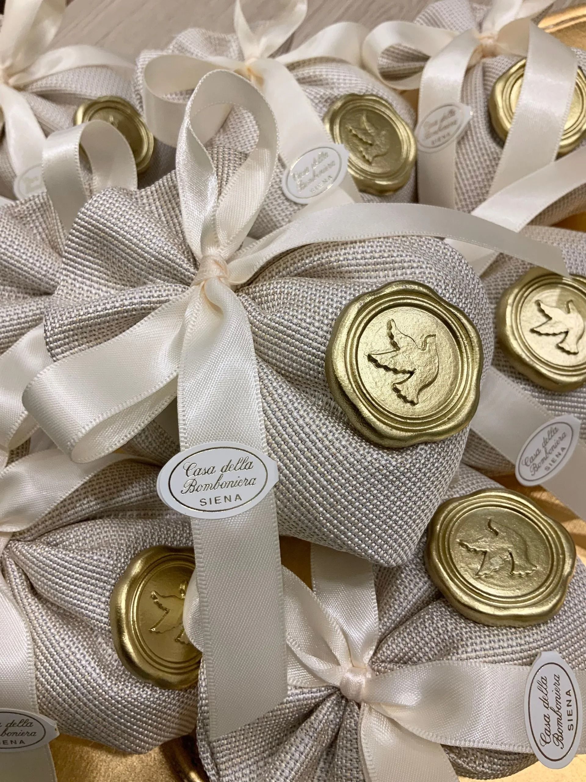 Sacchetto regalo in raso bianco, legato con un nastro, contenente monete di cioccolato dorate e piccole etichette decorative.