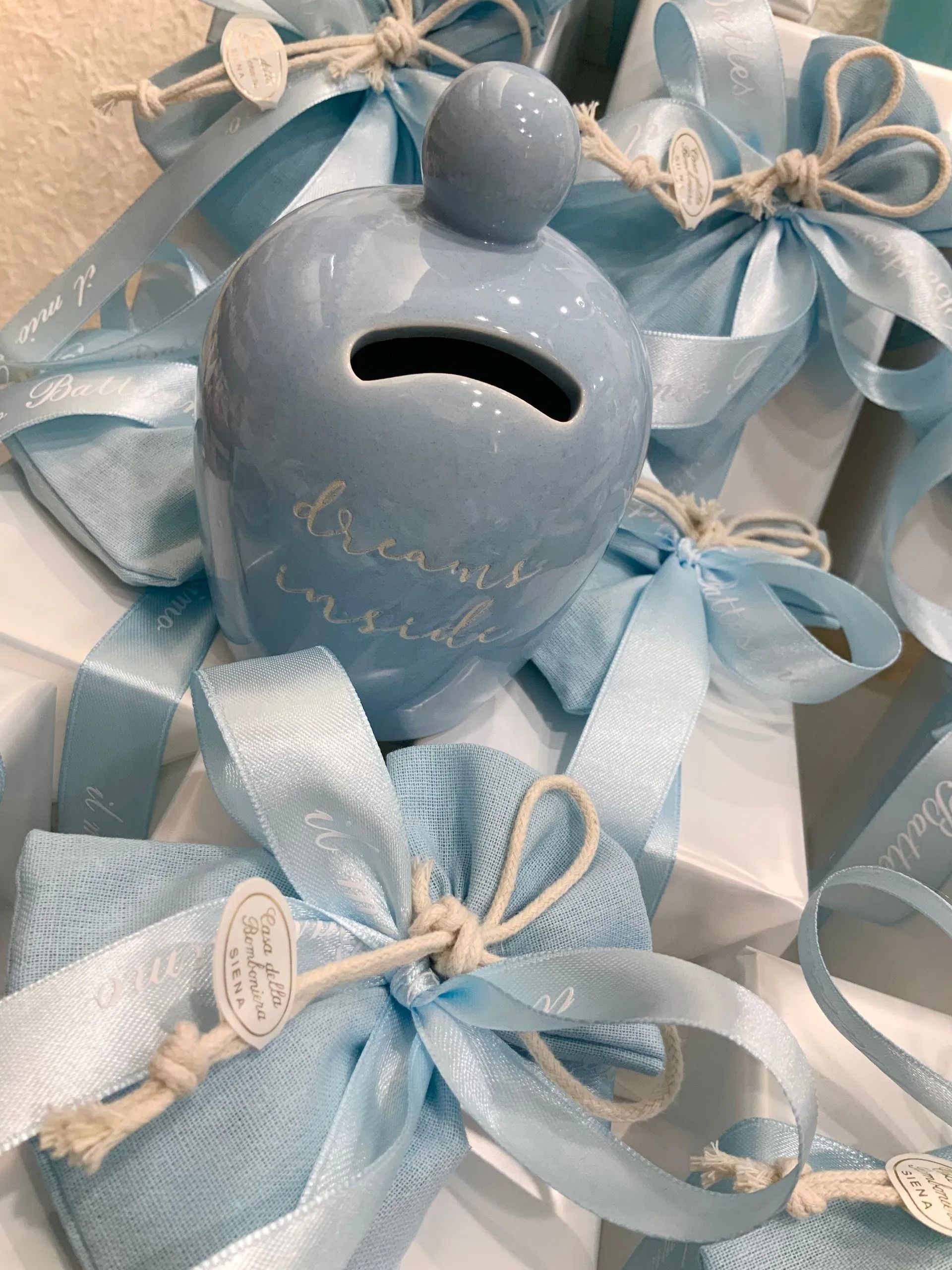 Salvadanaio blu e argento con regali incartati con nastri e fiocchi di spago, disposto a mo' di decorazione festiva.
