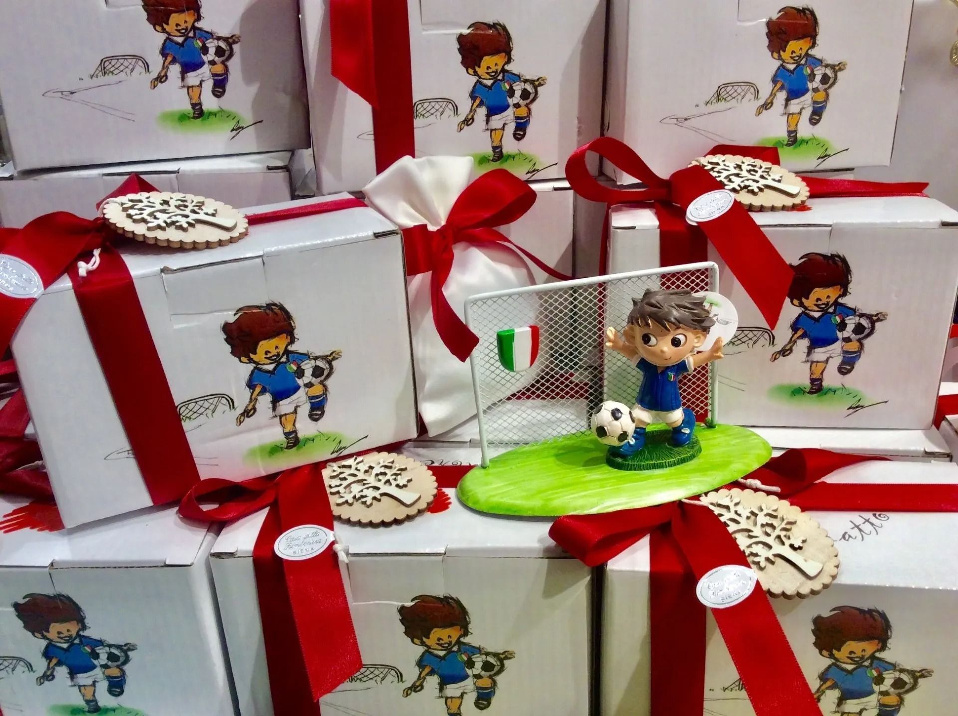 Scatole regalo incartate con nastri rossi e una piccola statuetta giocattolo su una base verde