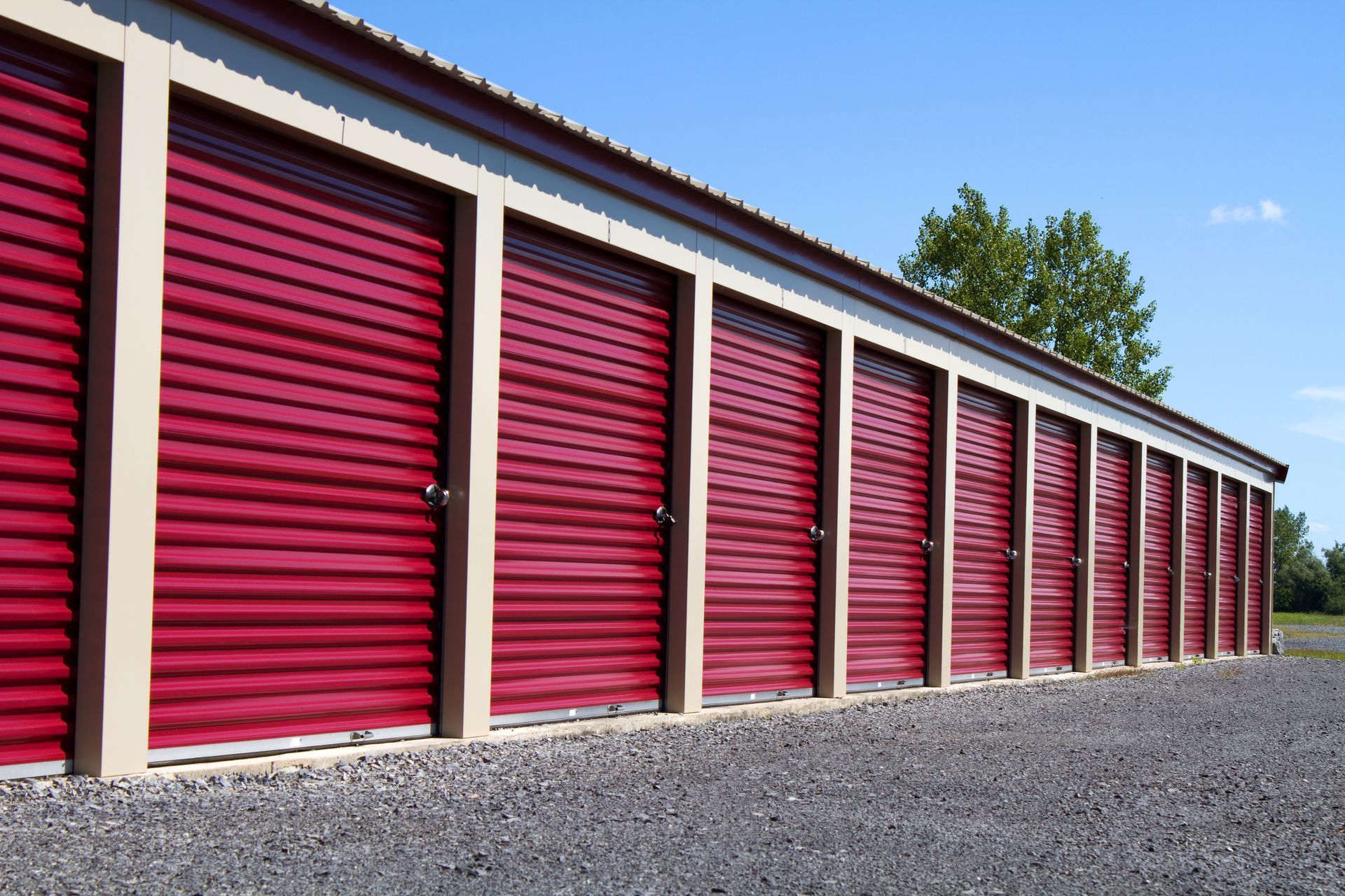 Row of red self-storage units with roll-up doors providing secure outdoor storage access.