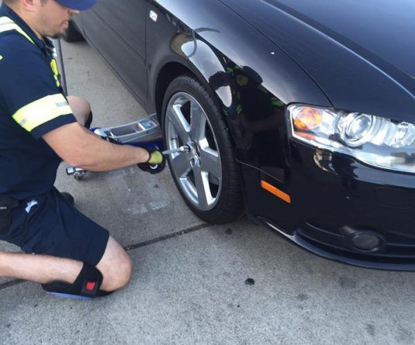 A man is changing a tire on a black car