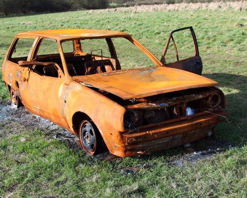 An old rusty car is sitting in a grassy field.