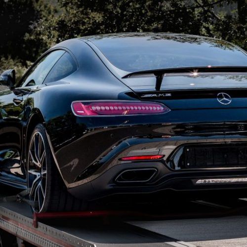 A black sports car is being towed by a tow truck