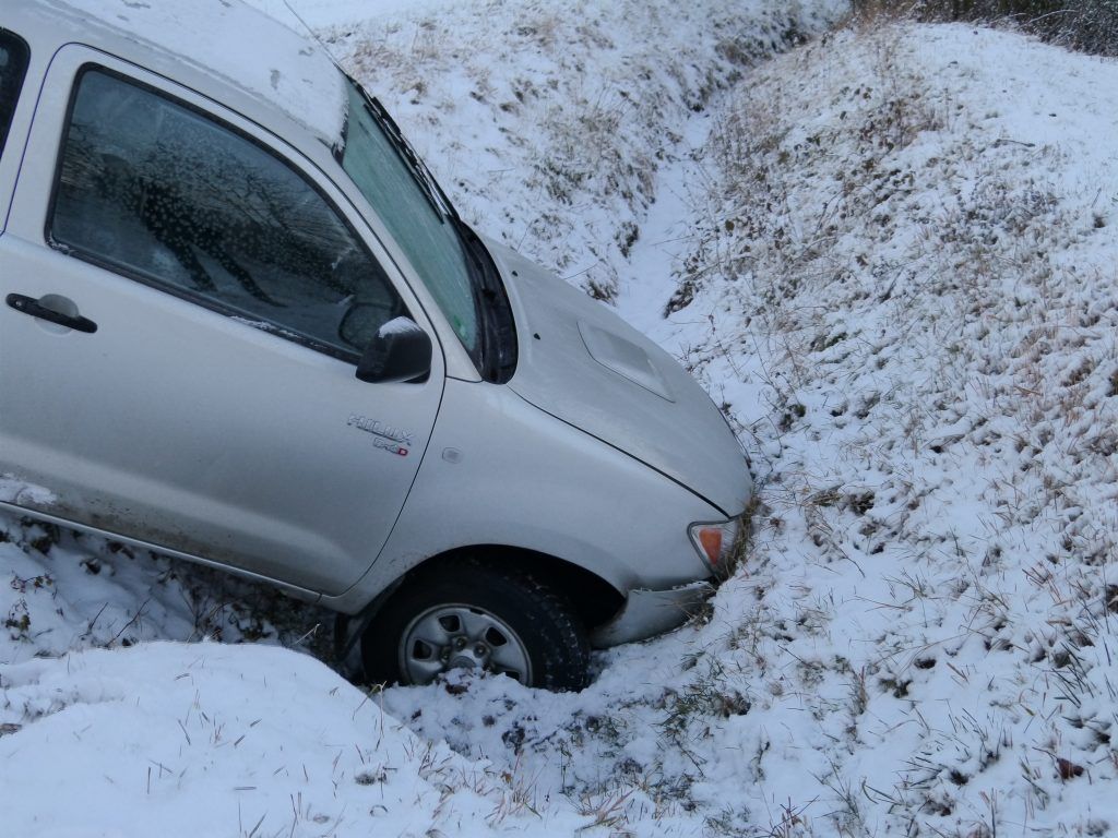 A silver car is stuck in the snow