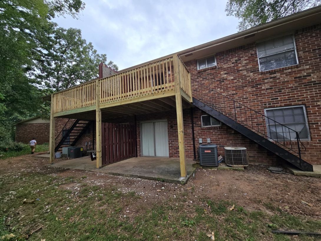 Brick house exterior with wooden deck staircase and covered patio underneath