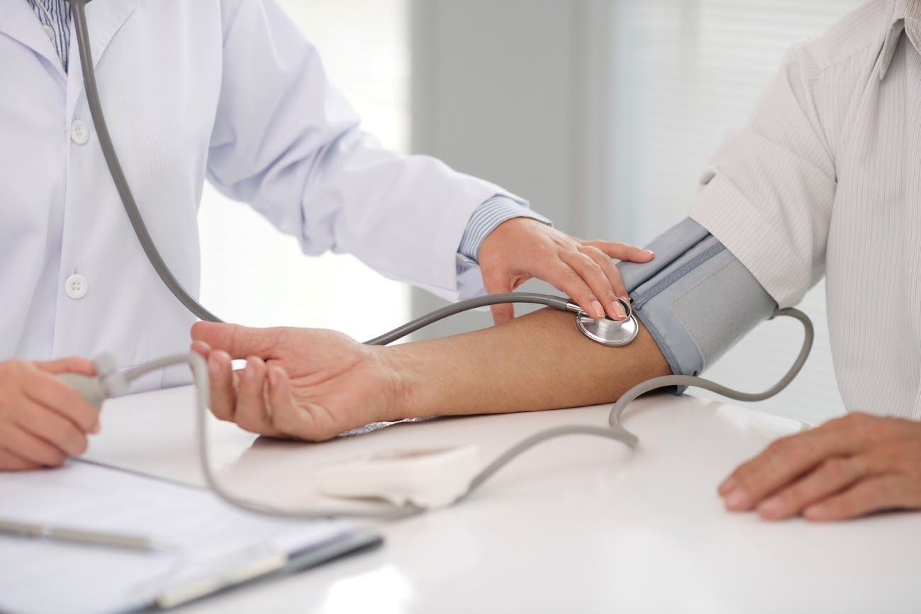 Il medico misura la pressione sanguigna del paziente con un bracciale sul suo braccio.