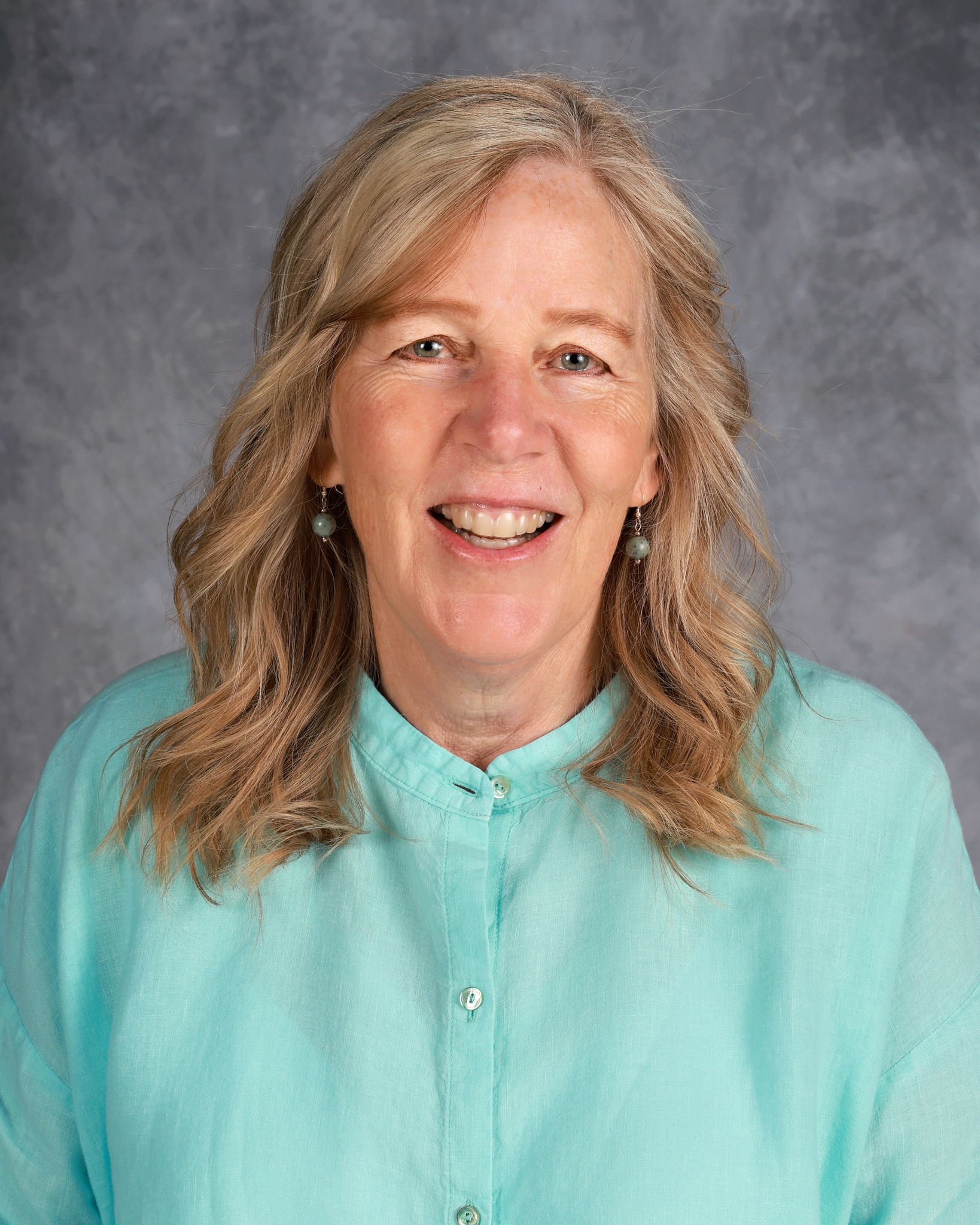Woman in tan shirt smiling at camera
