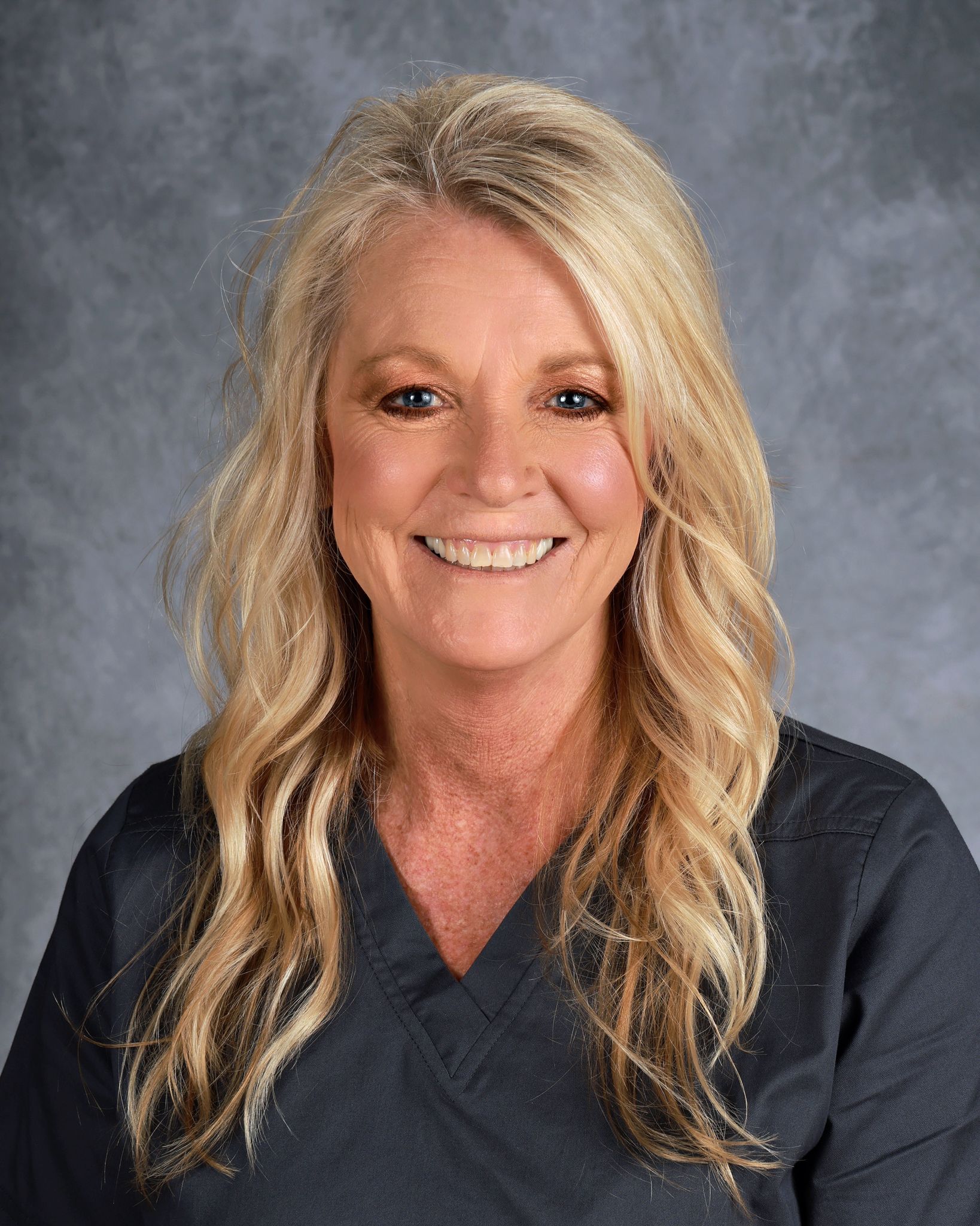 Woman in dark shirt smiling at camera.
