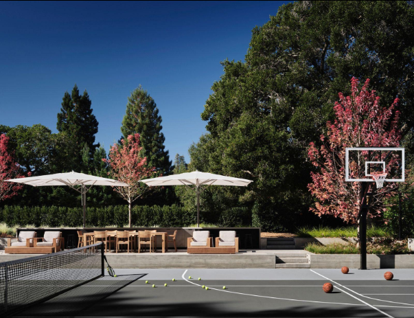 Private backyard basketball hoop beside an outdoor patio surrounded by trees after a court installation service in Peoria, AZ