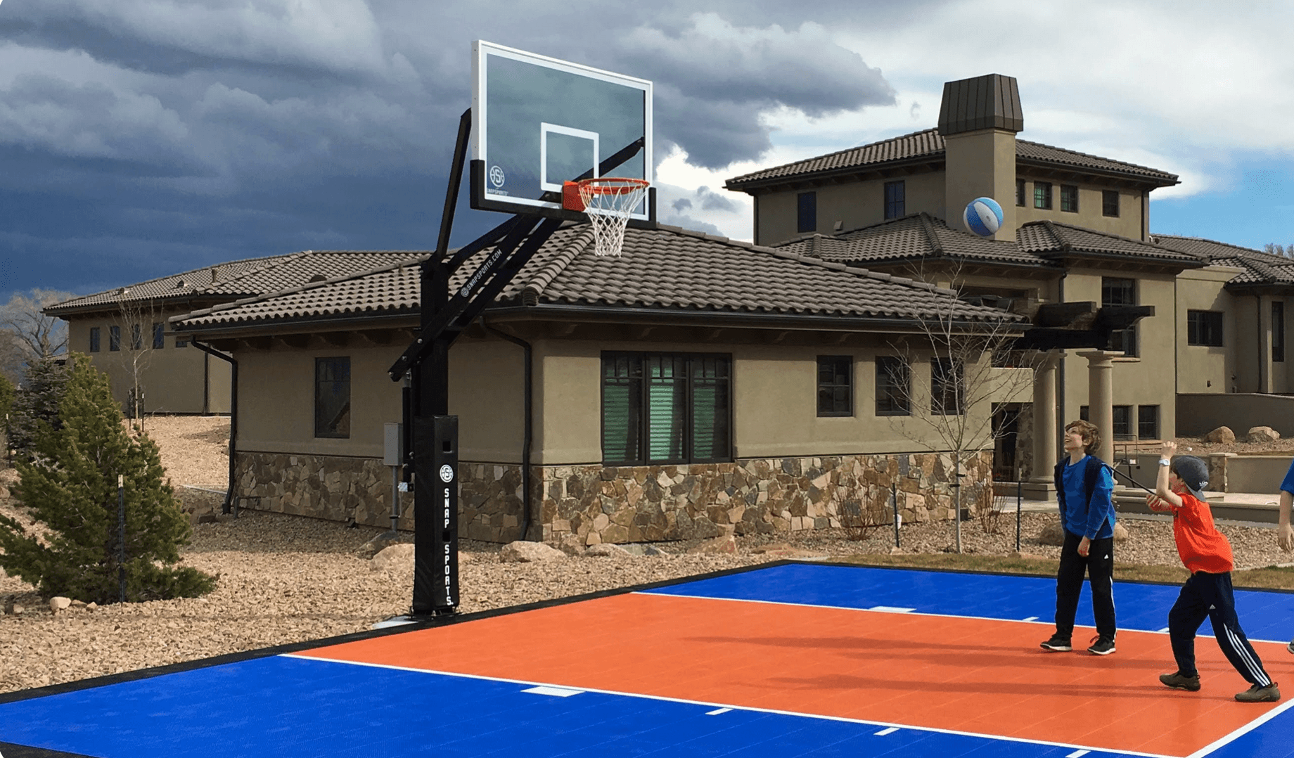 Children playing basketball on a colorful residential outdoor court beside a luxury home during a court installation service in Peoria, AZ