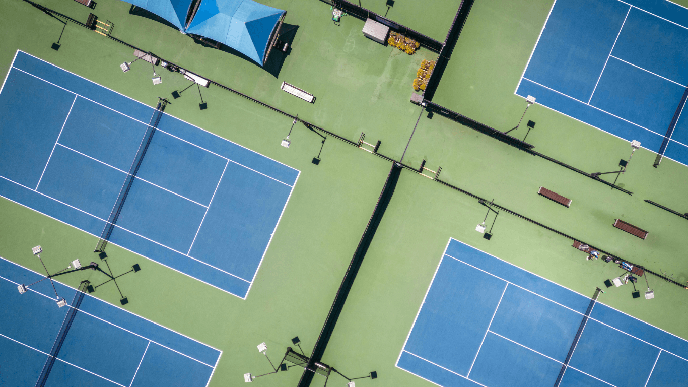 Aerial view of multiple blue sport courts with players and walkways inside a large recreational complex during a court installation service in Peoria, AZ