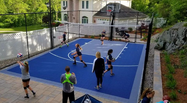 Players enjoying a backyard basketball game on a newly installed blue sport court during a court installation service in Peoria, AZ