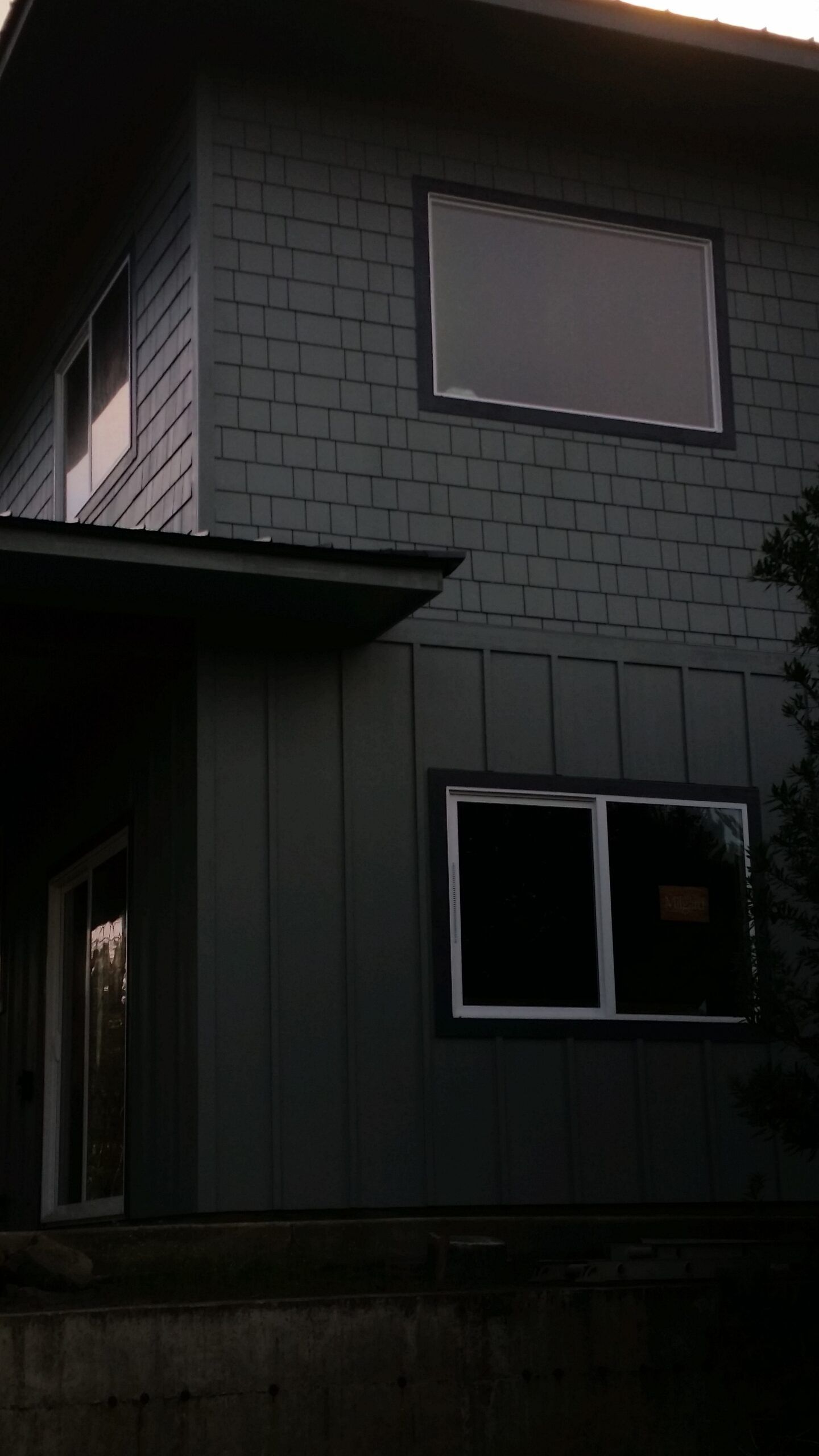Dark gray house exterior with two windows and a sloped roofline.