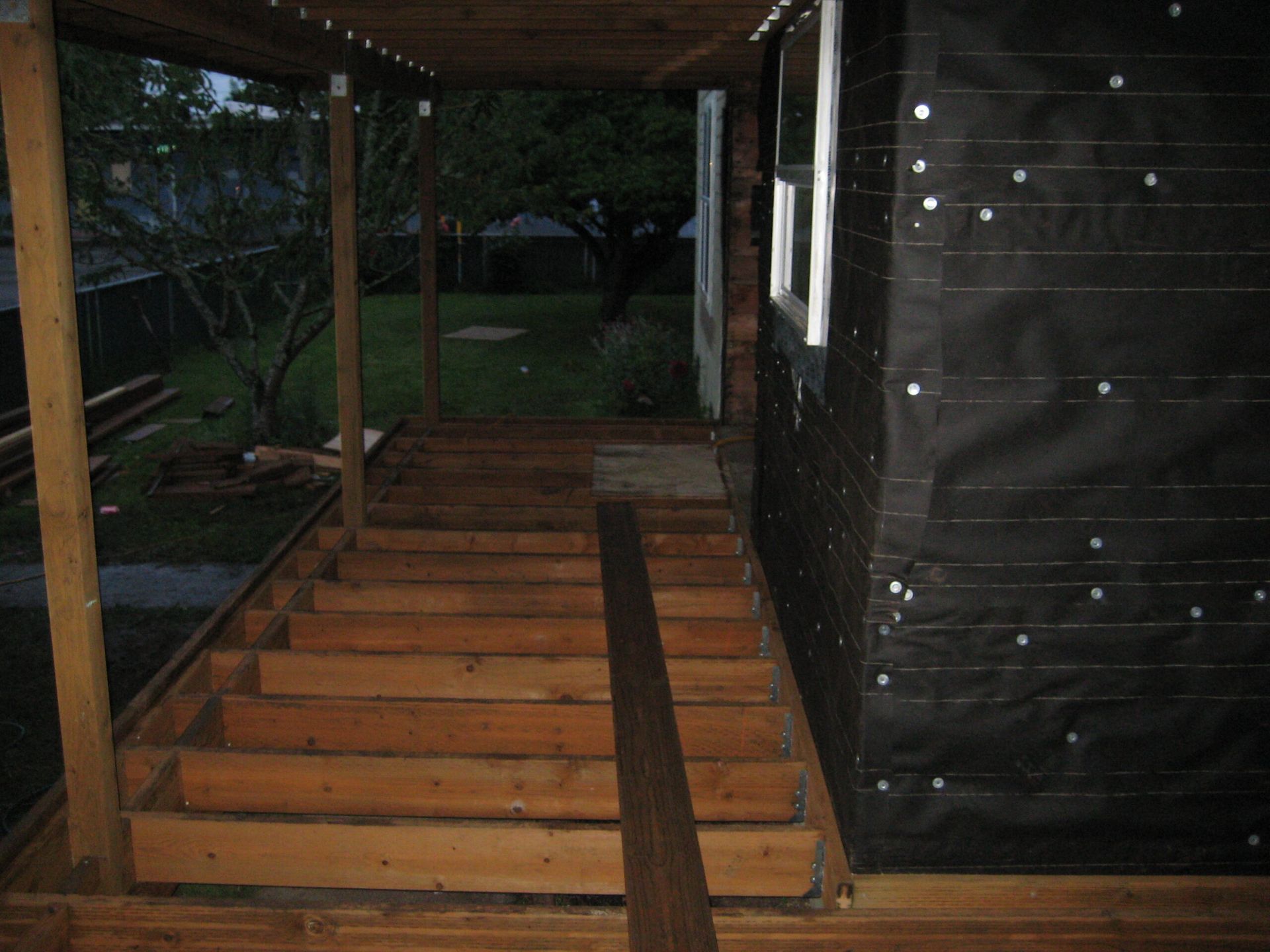 Wooden ramp and steps leading to a porch in a dark, rainy outdoor setting