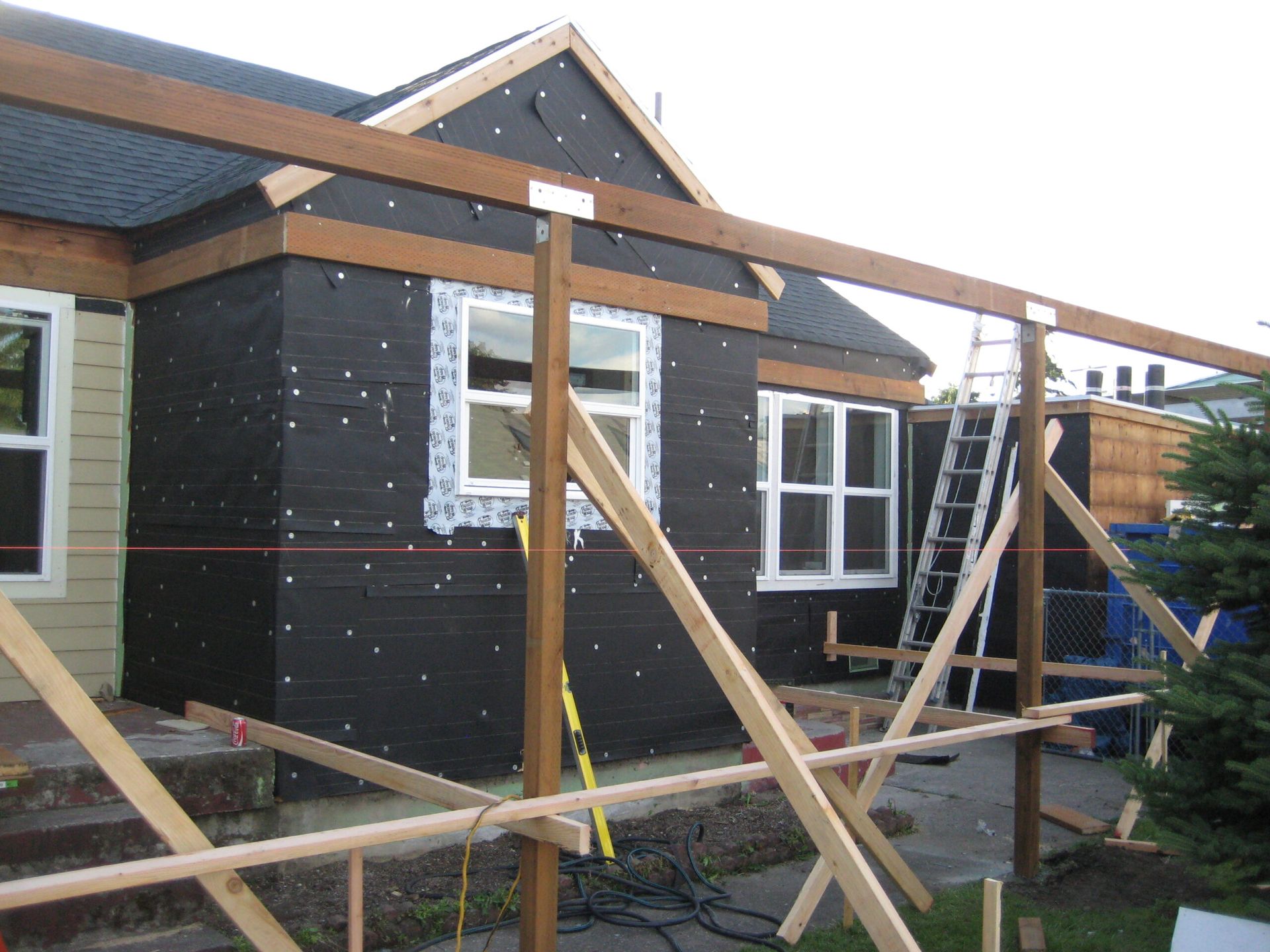 Black house exterior under construction with wooden framing and scaffolding in front