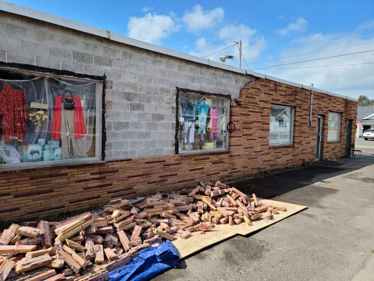 Damaged building exterior with broken windows and a pile of bricks and debris along the wall