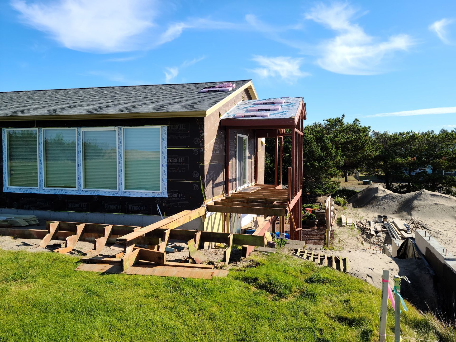 Damaged seaside house with broken steps and sandy erosion under a blue sky