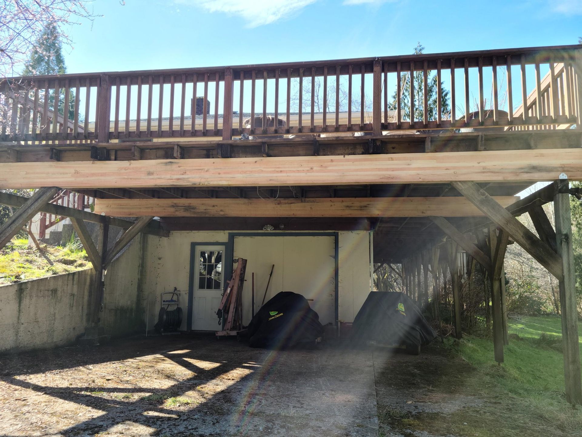 Backyard deck over a carport with stairs, wooden railings, and a small shed below