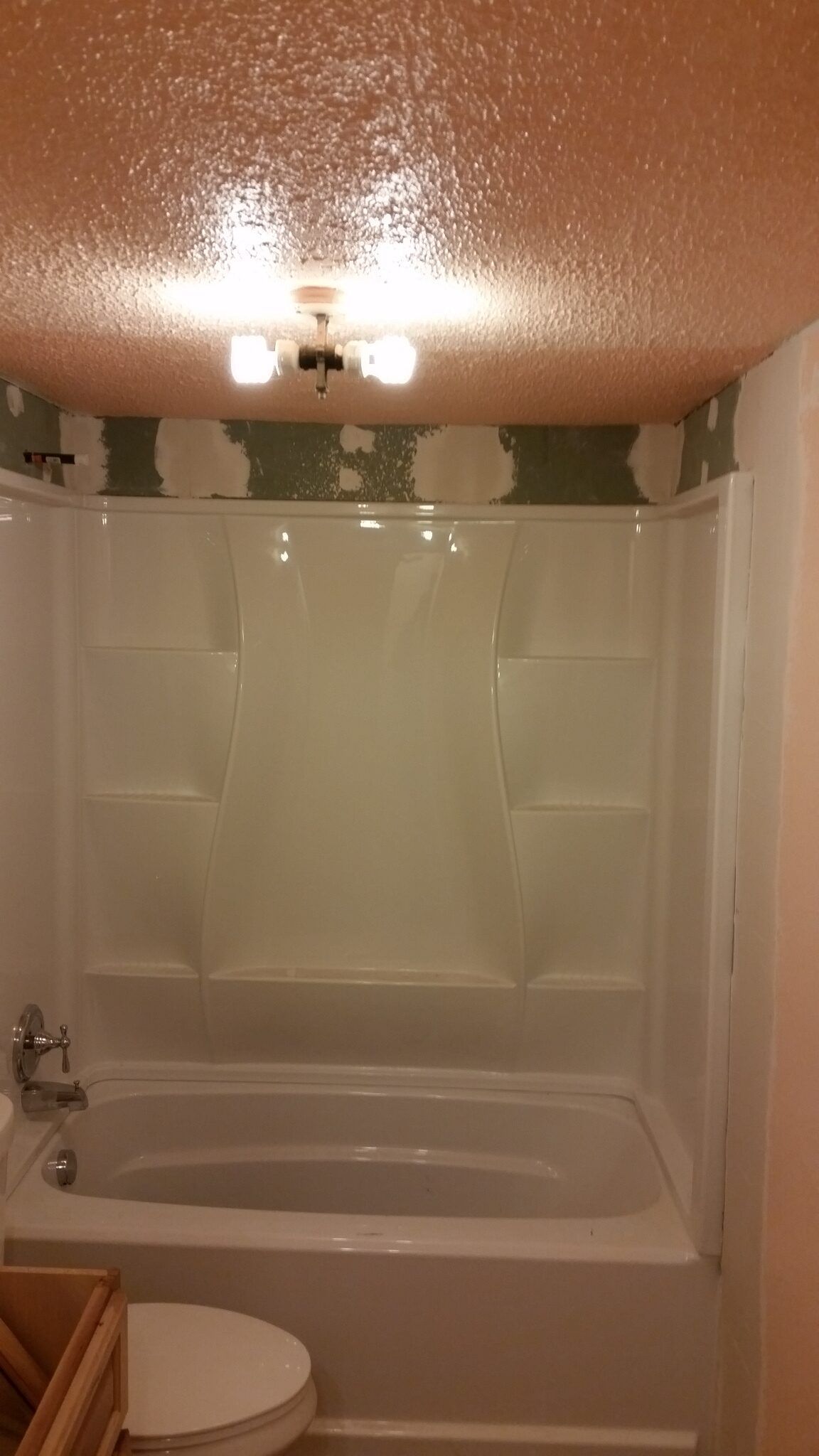Bathroom with white tub and shower curtain under a ceiling light and patterned wall trim.