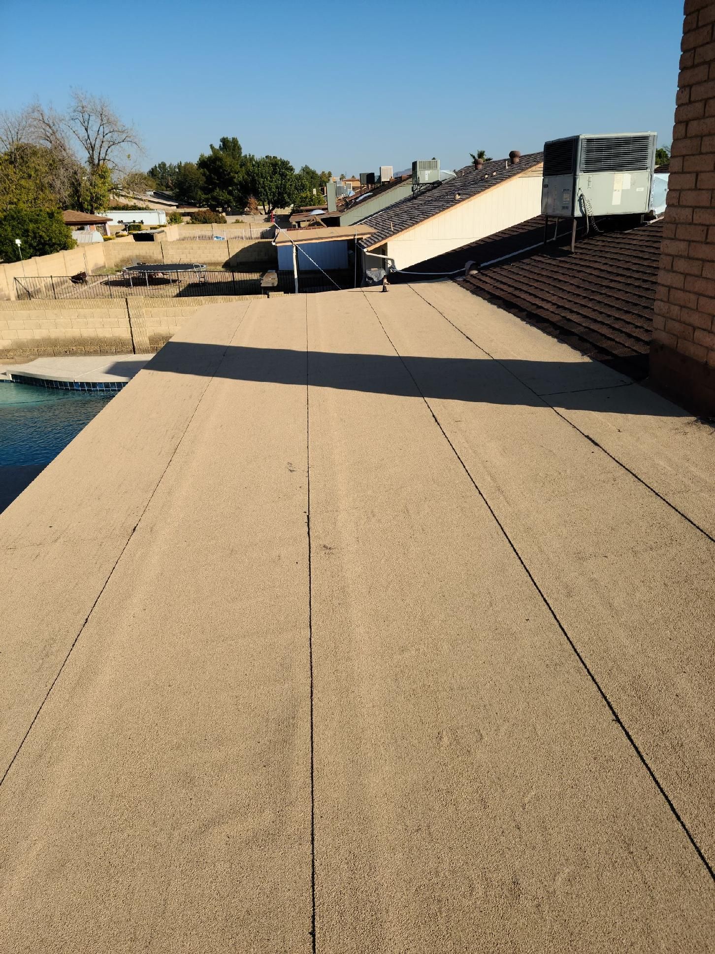Flat rooftop walkway with brick wall and solar panels under a clear blue sky