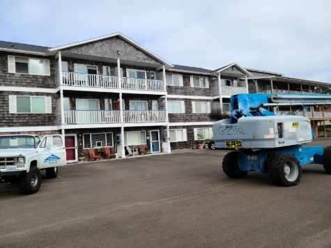 Apartment building parking lot with two utility trucks, one blue lift truck in the foreground