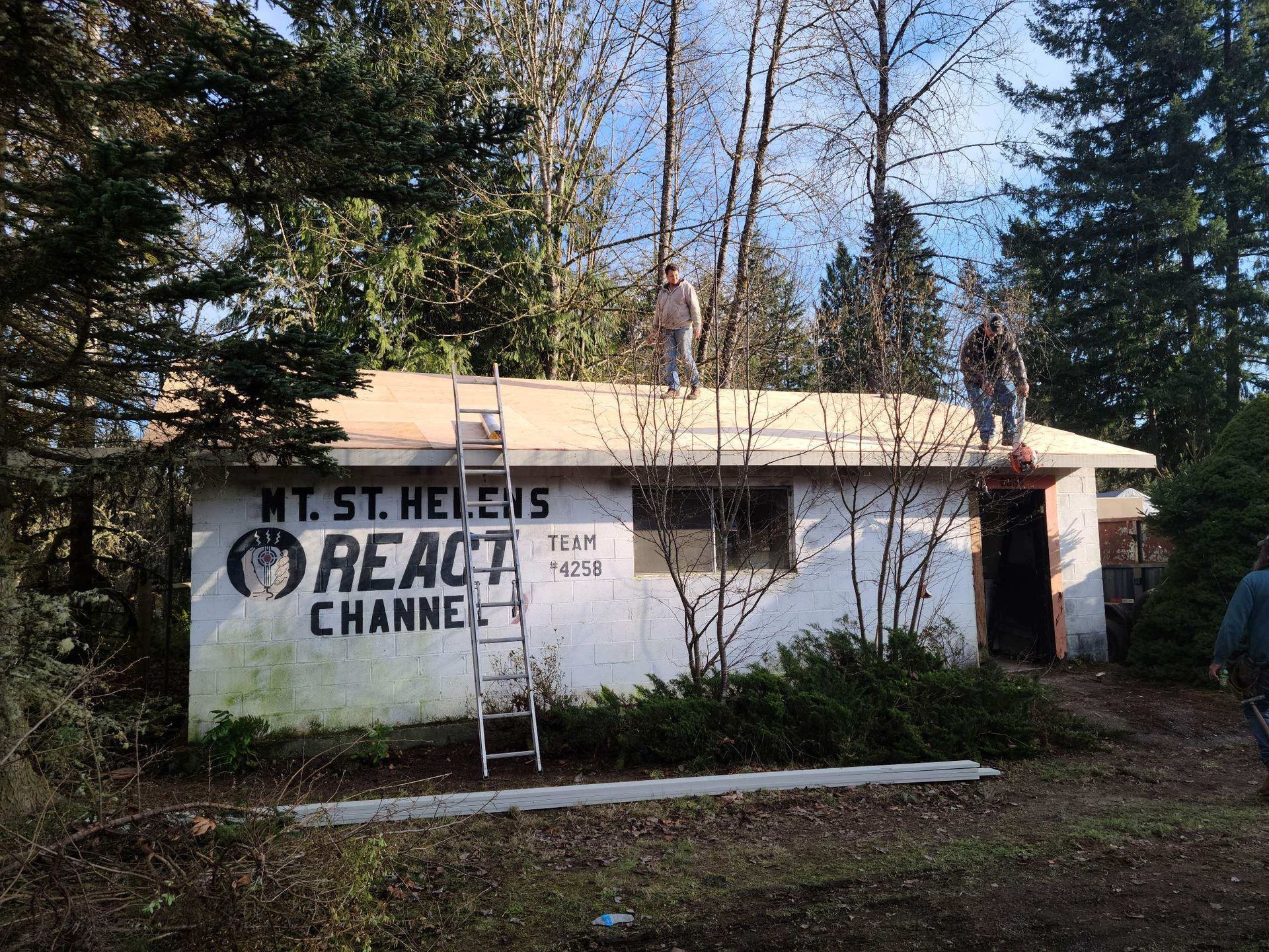 Graffiti on an abandoned white building amid trees, with a person walking at the right edge.