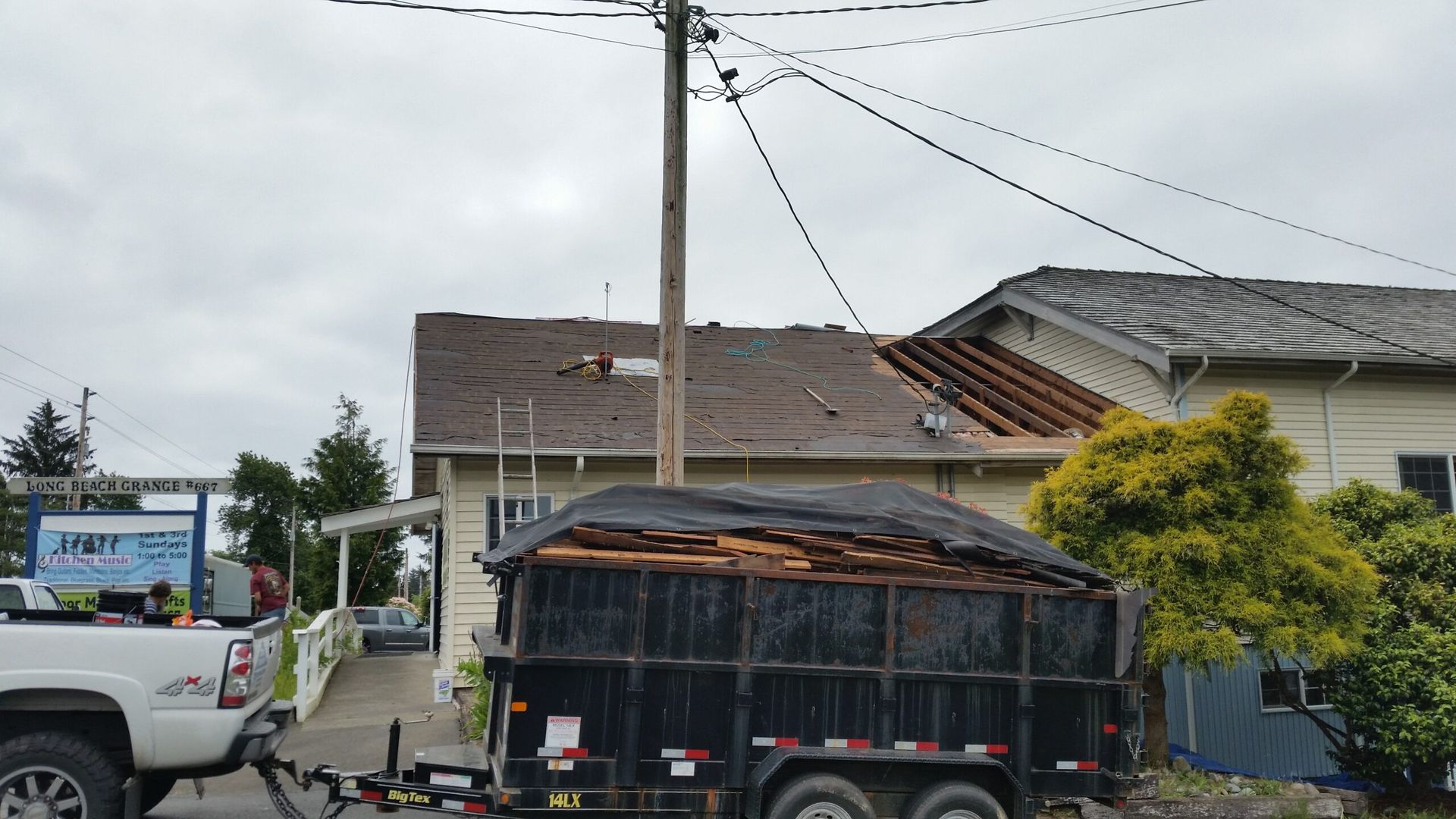 Black trailer covered with a tarp parked by a utility pole in a residential street.