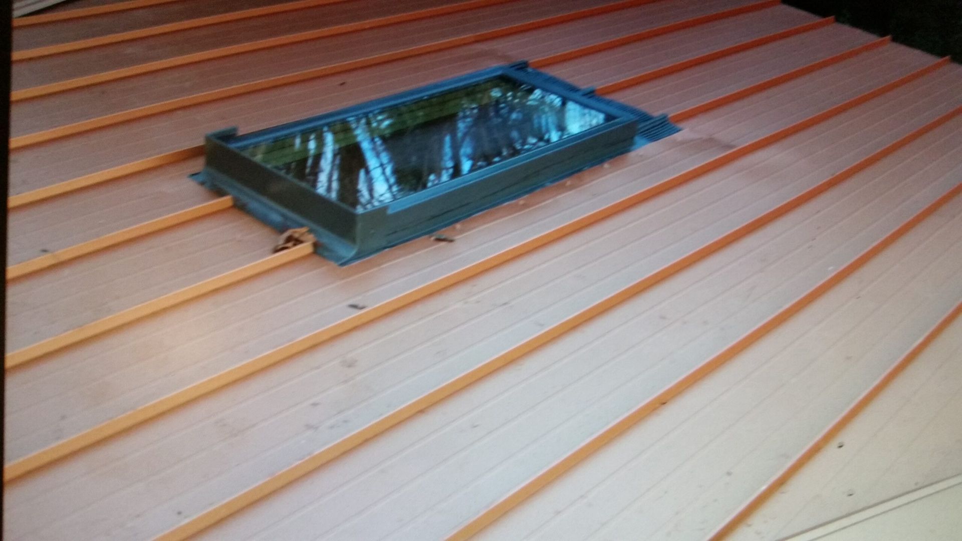 Rectangular skylight set into a light wooden slatted roof panel.