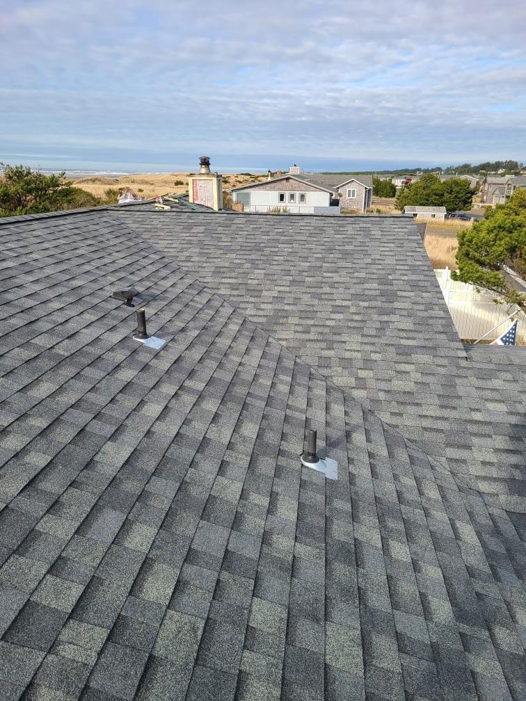 Gray shingled rooftop overlooking a coastal neighborhood and the ocean beyond