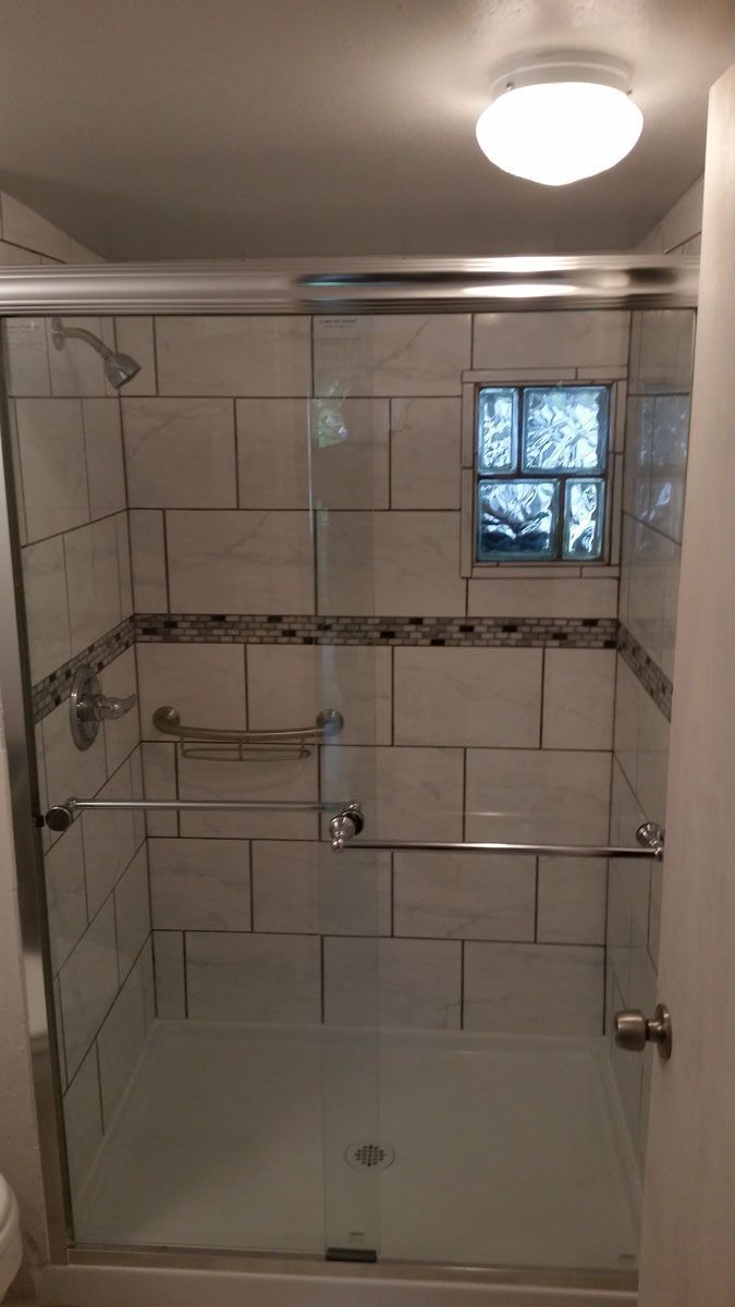 Accessible shower with grab bars, fold-down seat, and tiled walls in a bathroom