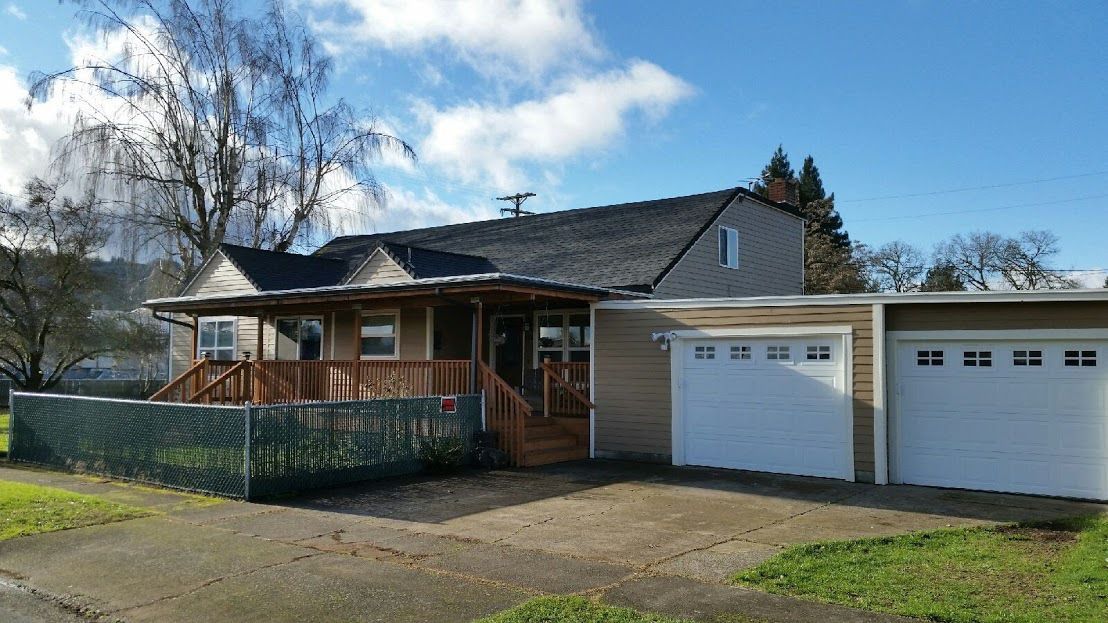 Suburban house with a front porch and two white garage doors on a sunny day