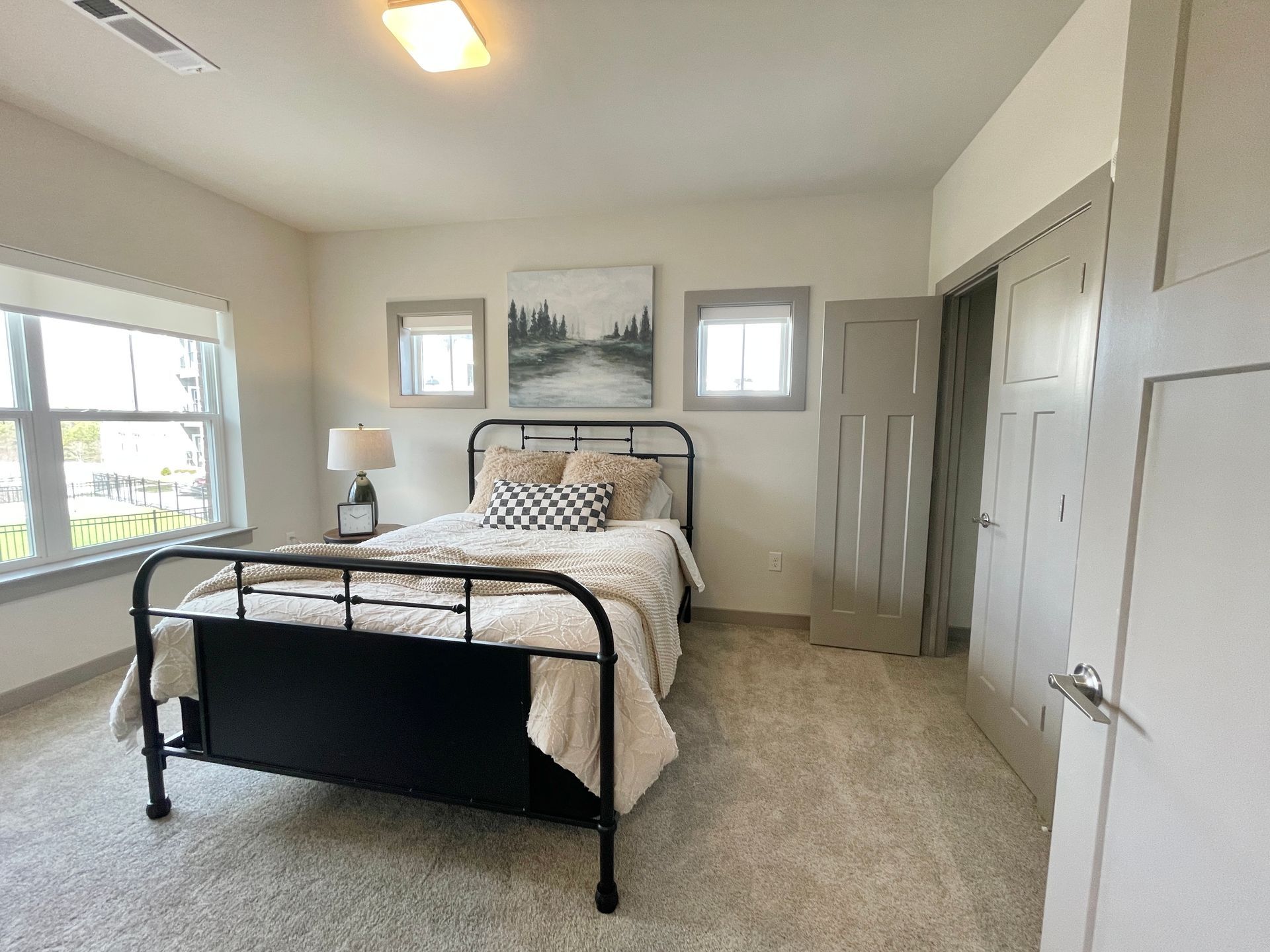 A bedroom with a bed , two windows and a closet.