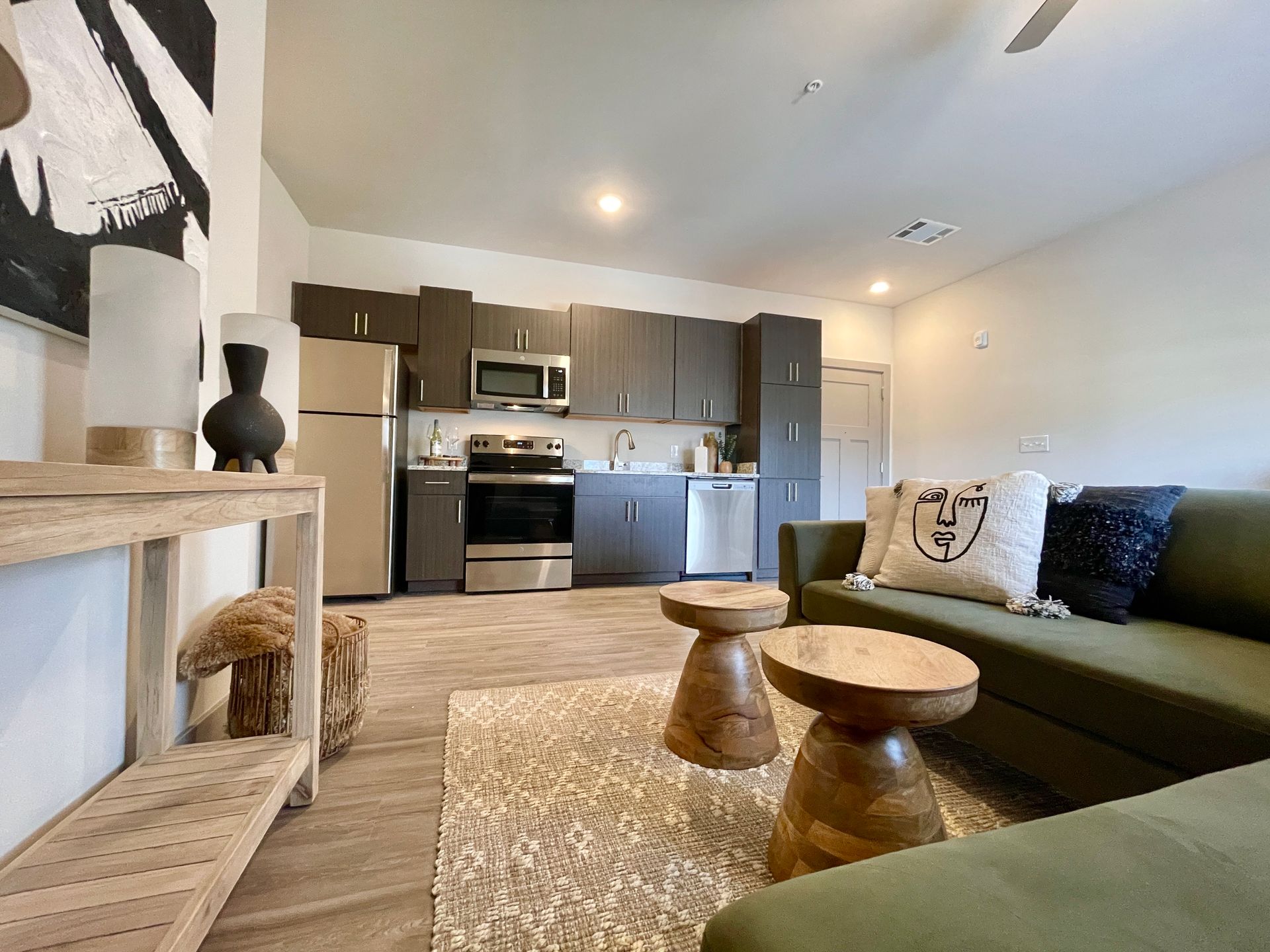 A living room with a green couch and a kitchen in the background.