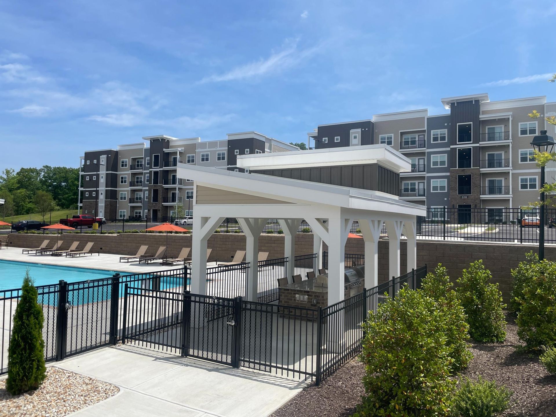 There is a gazebo with a grill in front of a swimming pool.