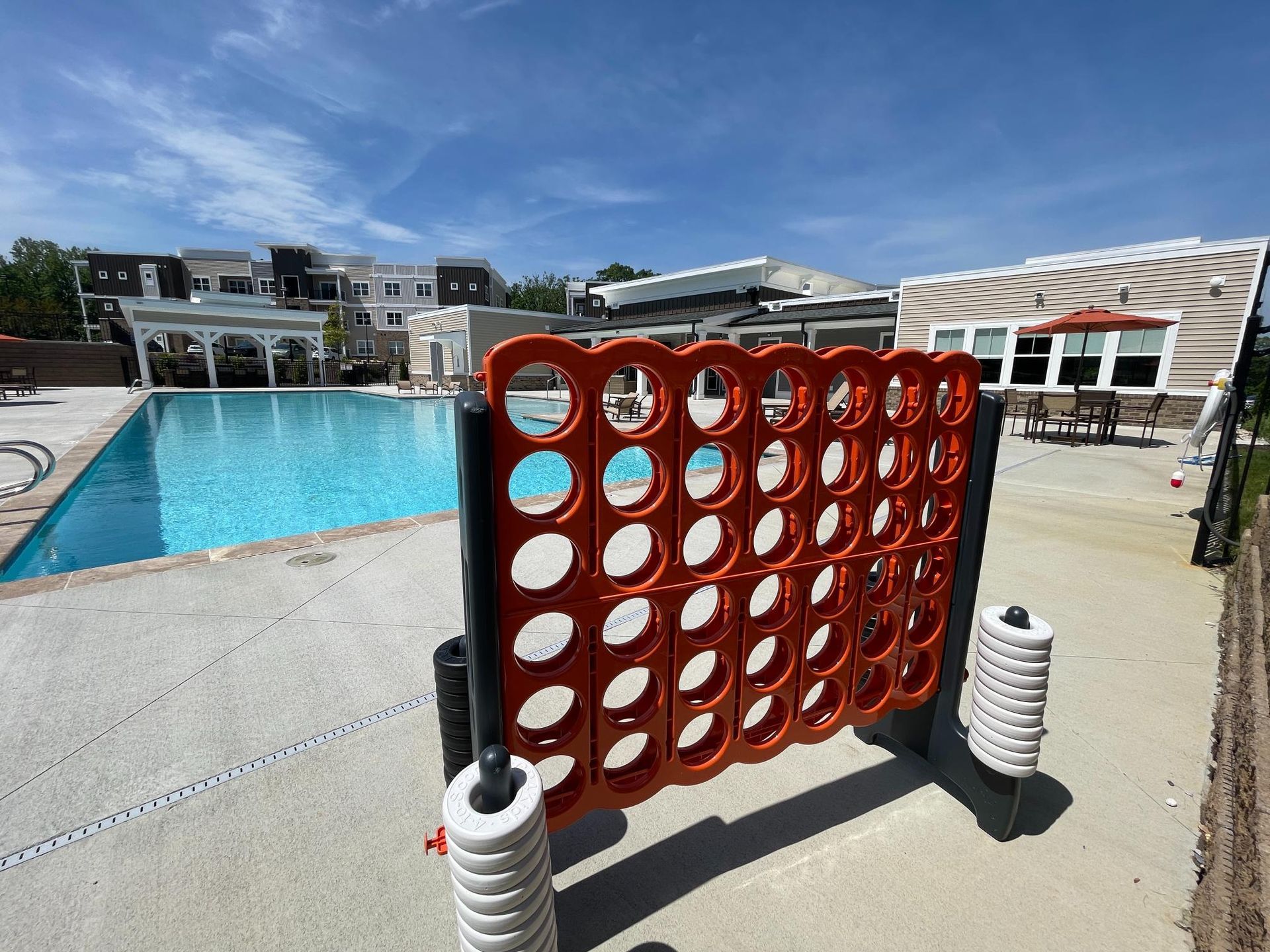 A giant connect four game is sitting in front of a swimming pool.
