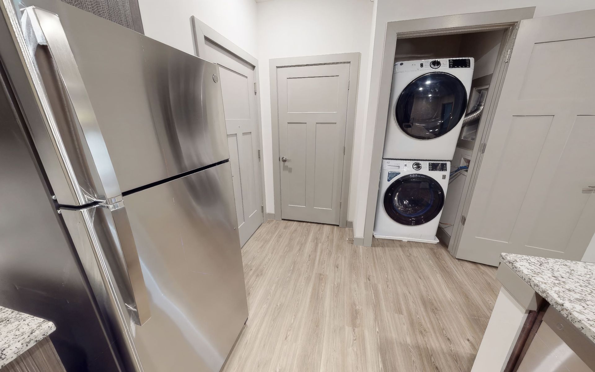 A kitchen with a refrigerator , washer and dryer stacked on top of each other.