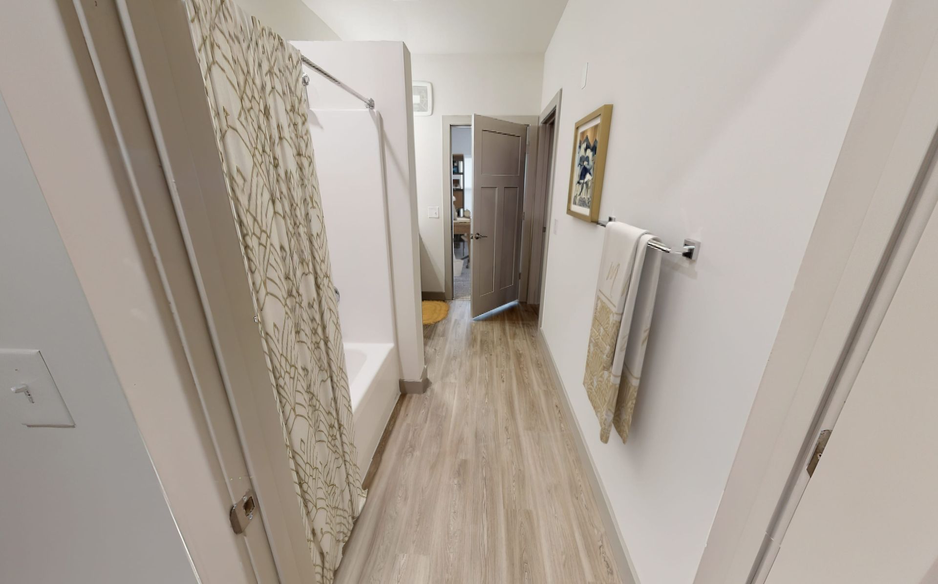 A hallway leading to a bathroom with a tub and shower.