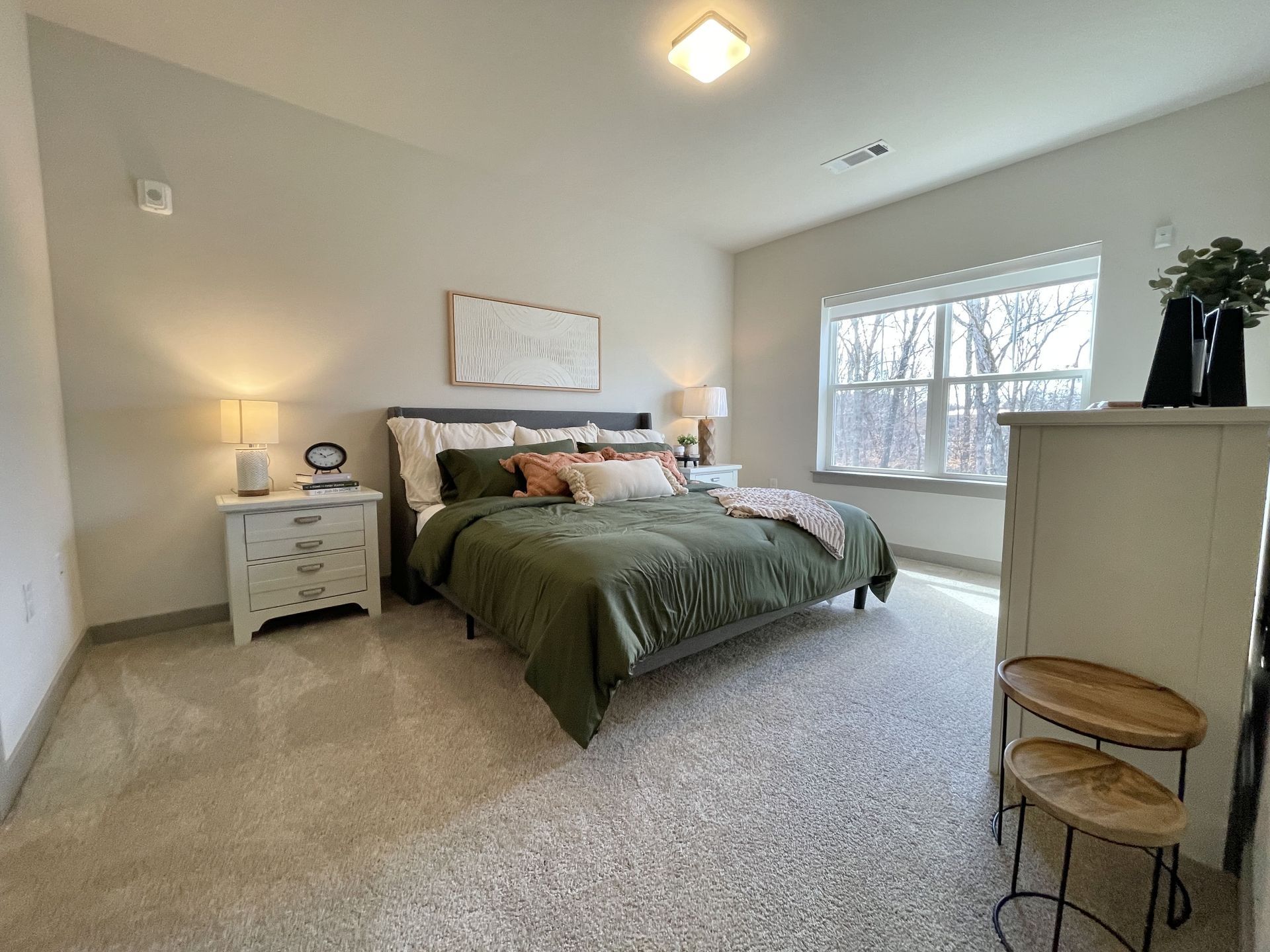A bedroom with a bed , nightstand , dresser and window.